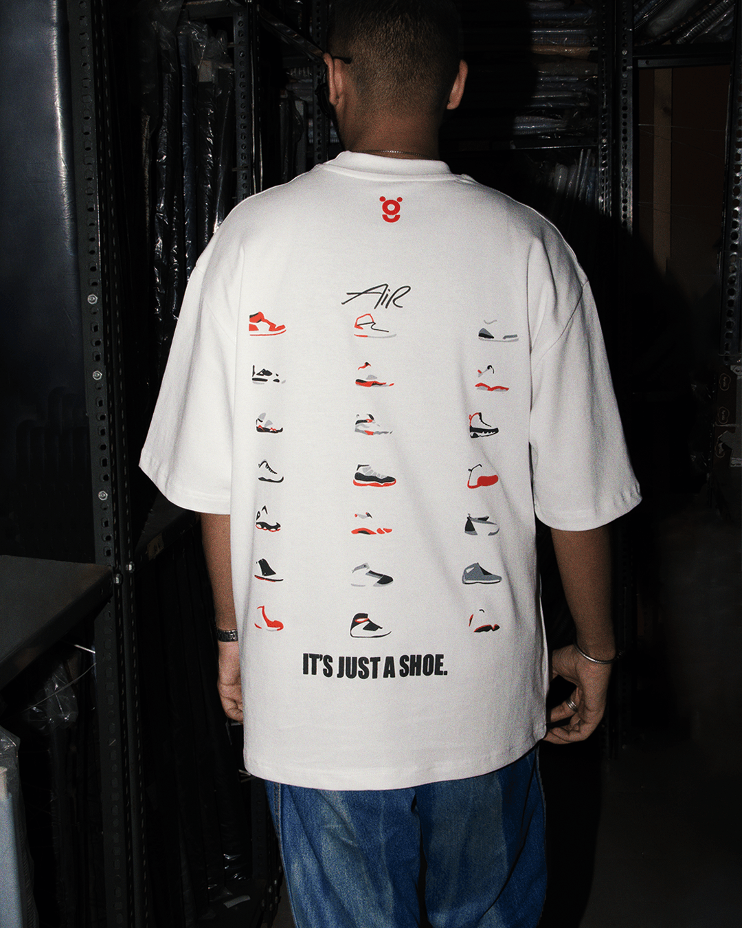 Man wearing white graphic streetwear tee with illustrated sneakers and 'It's Just a Shoe' text