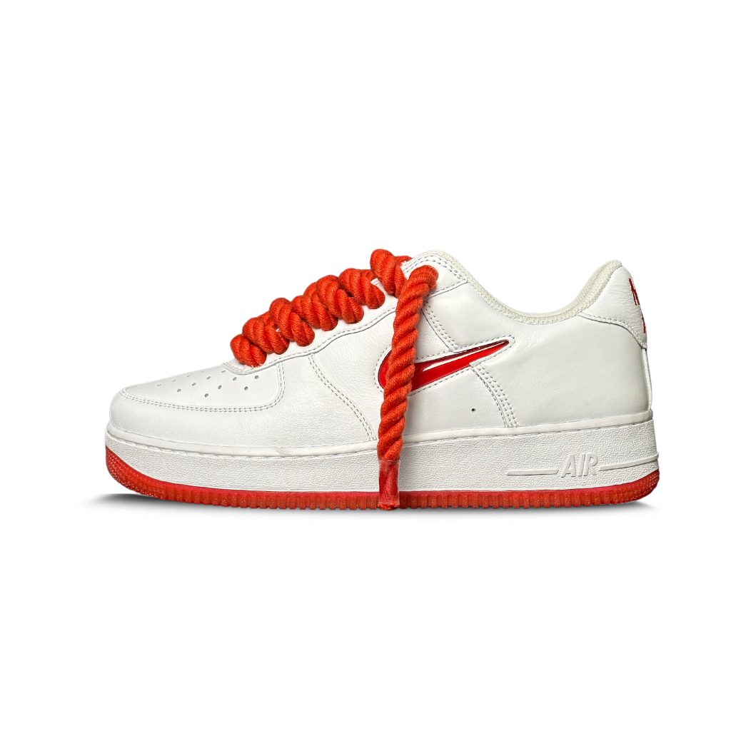 White low-top sneaker with thick red laces, red sole, and red side logo, isolated on white