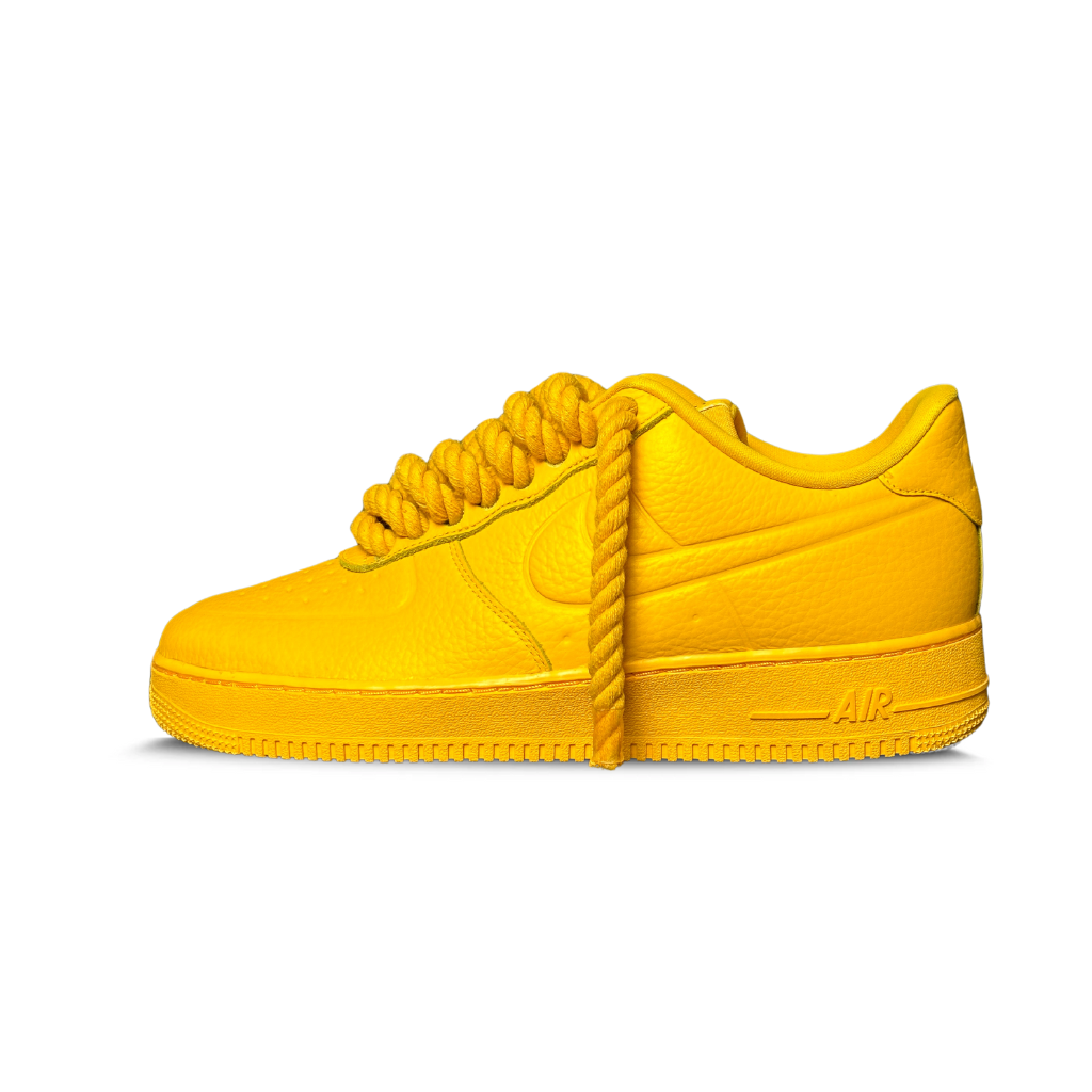 Bold yellow leather low-top sneaker with chunky rope laces, streetwear style, on white background