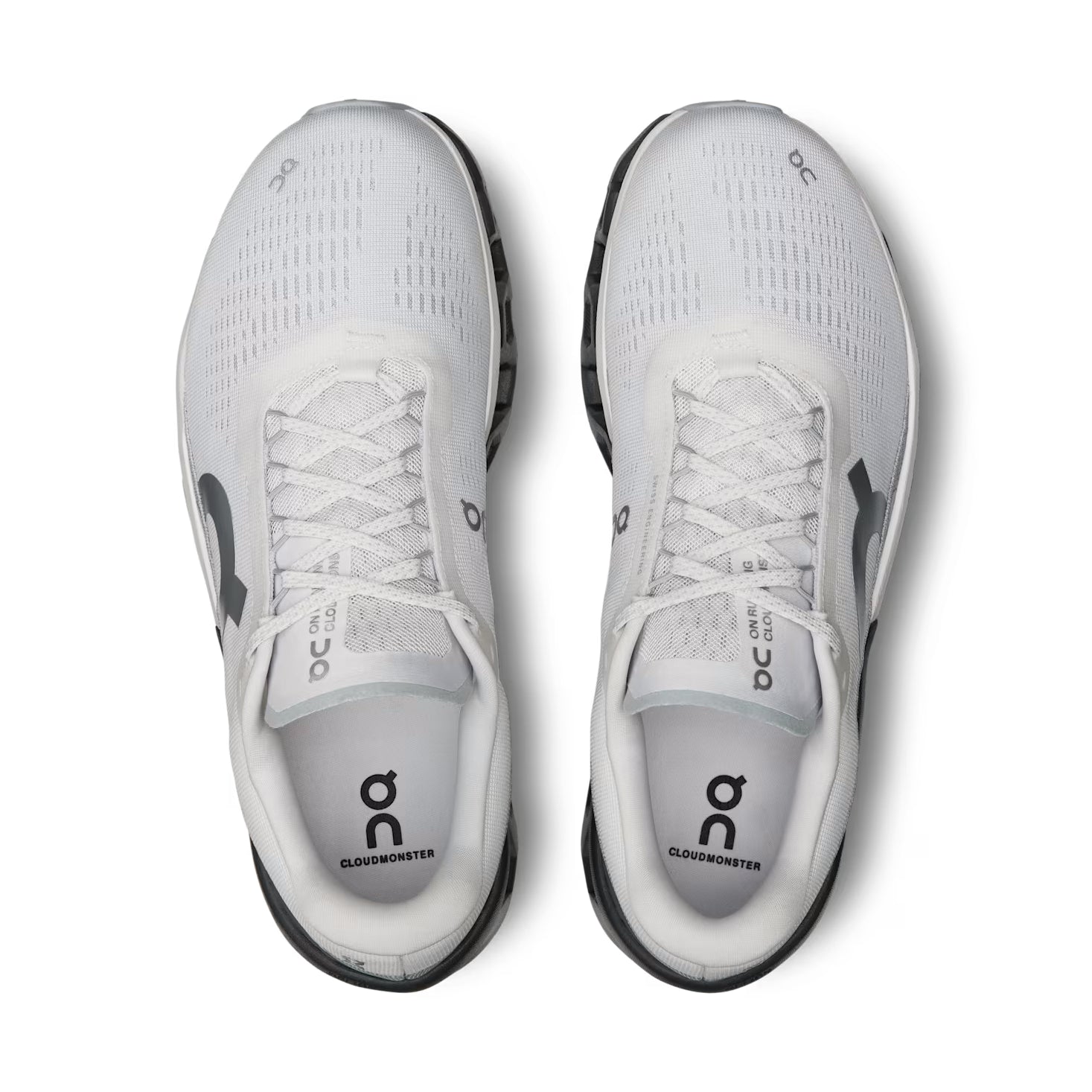 Pair of white On Cloudmonster running shoes with black soles, top view, mesh uppers, visible branding