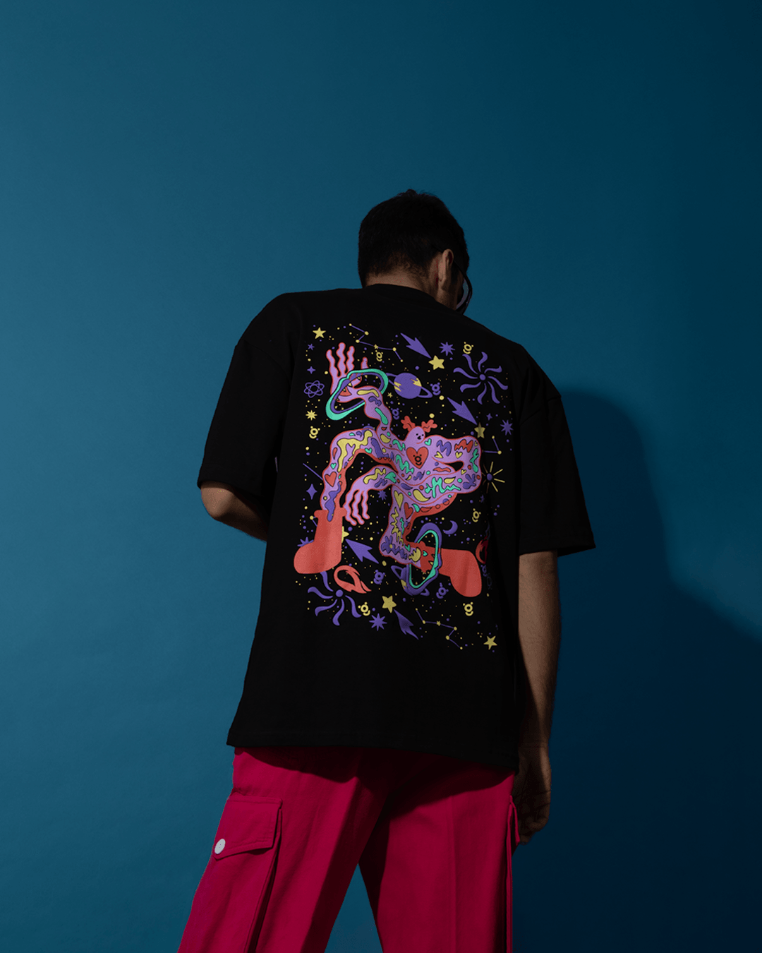 Man wearing black streetwear t-shirt with colorful abstract graphic and magenta cargo pants