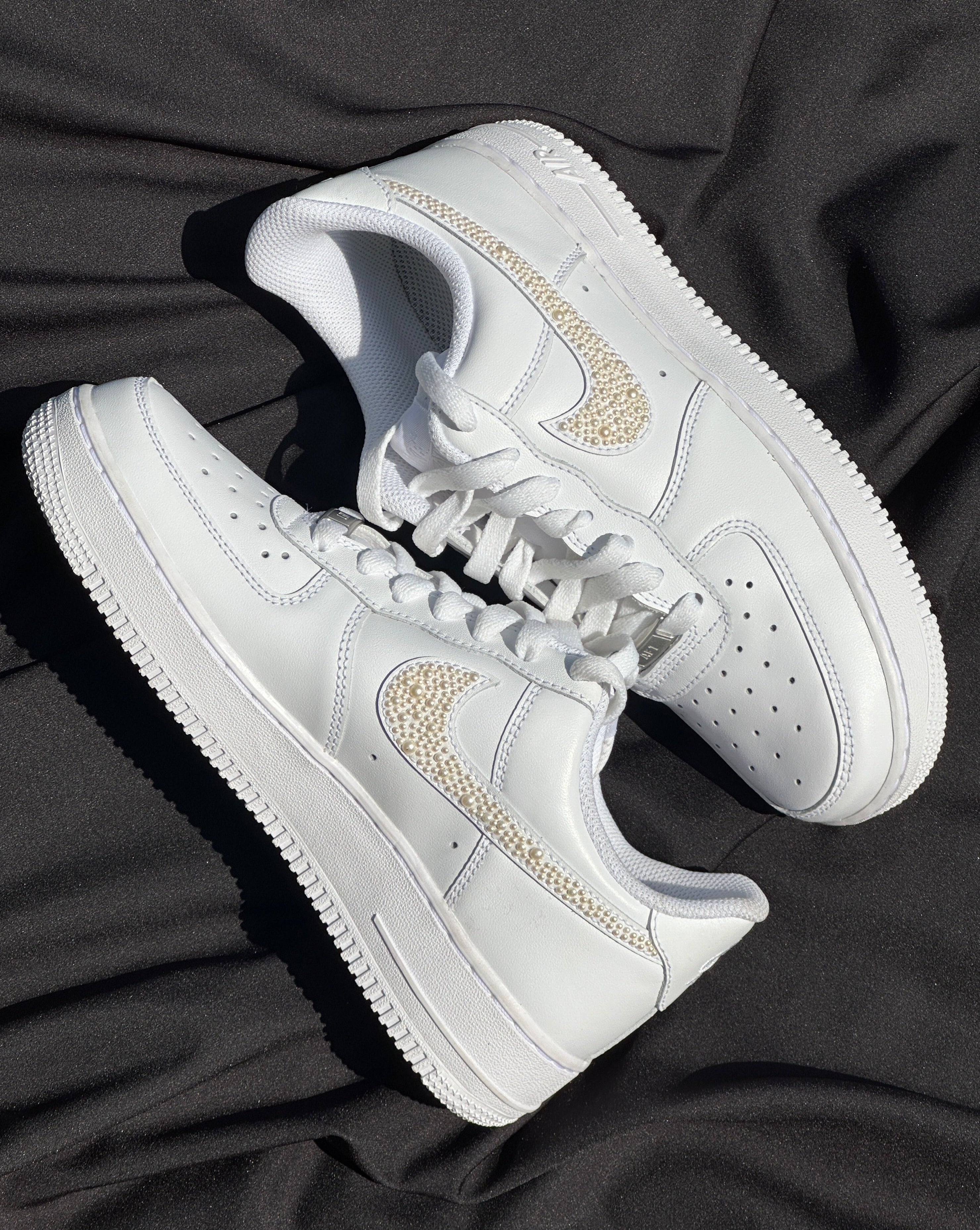 White leather streetwear sneakers with pearl-embellished Nike swoosh on black fabric