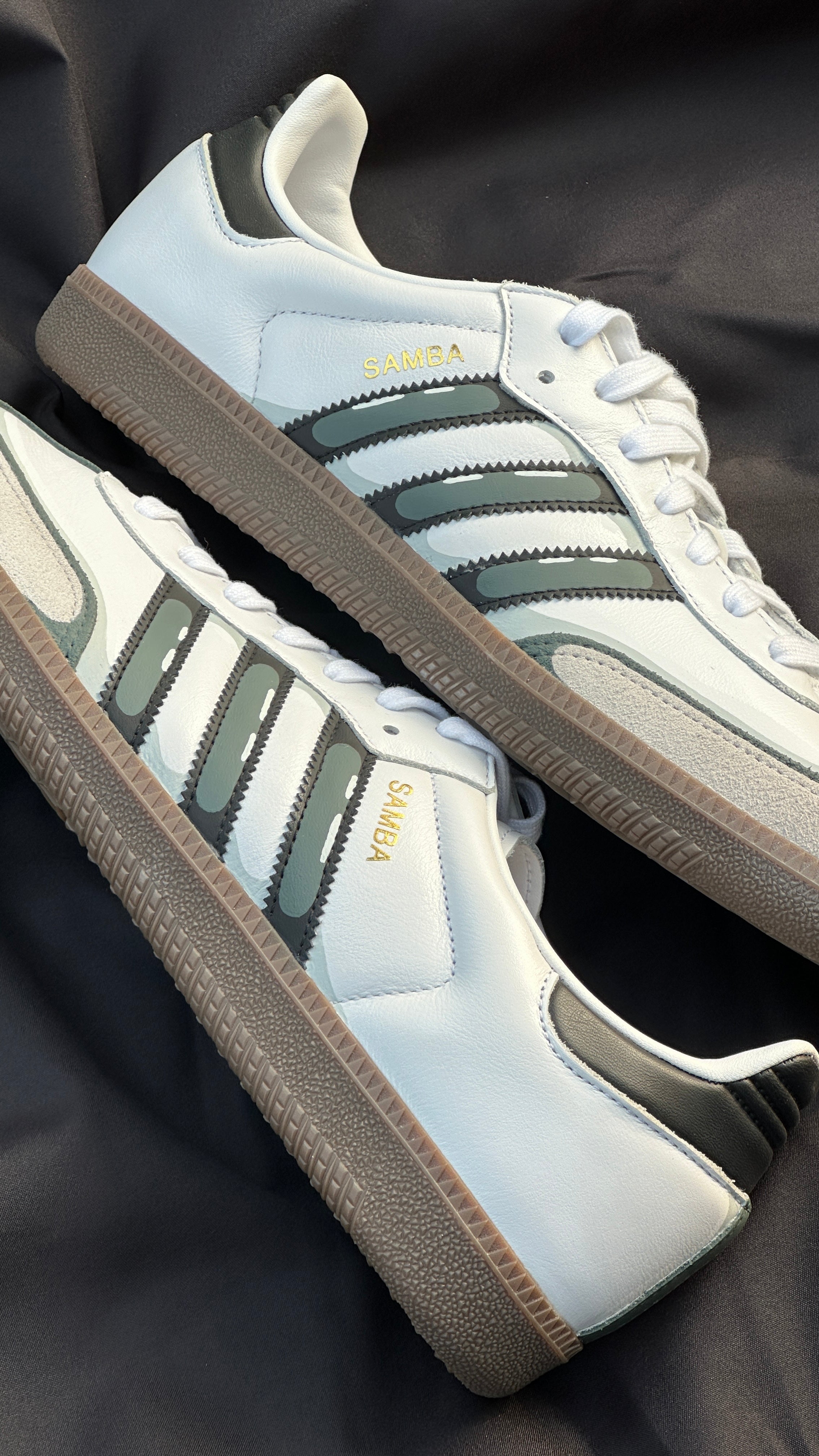 White and black Adidas Samba sneakers with gum soles on a dark background