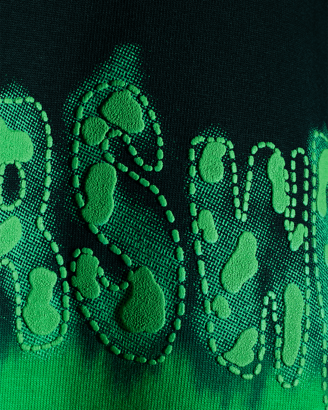 Close-up of green textured streetwear graphic print on black fabric