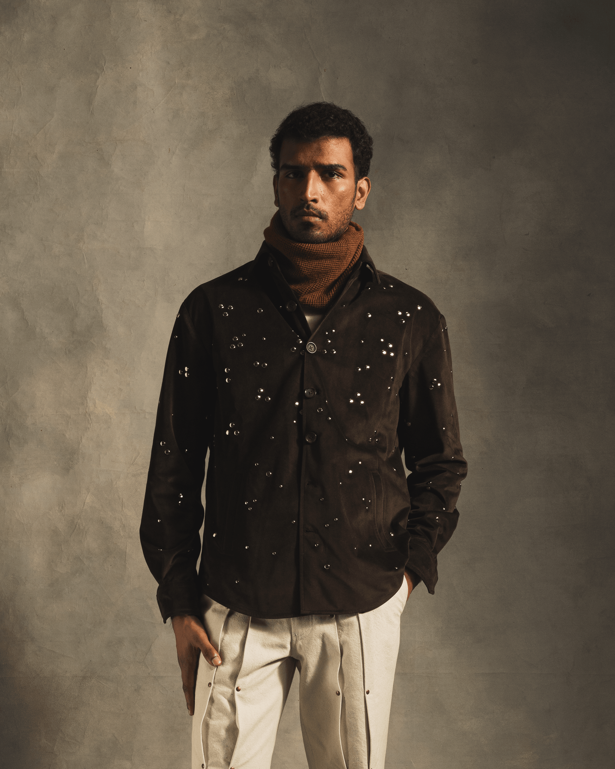 Man wearing a brown rivet shirt with perforated detailing and beige pants, streetwear style