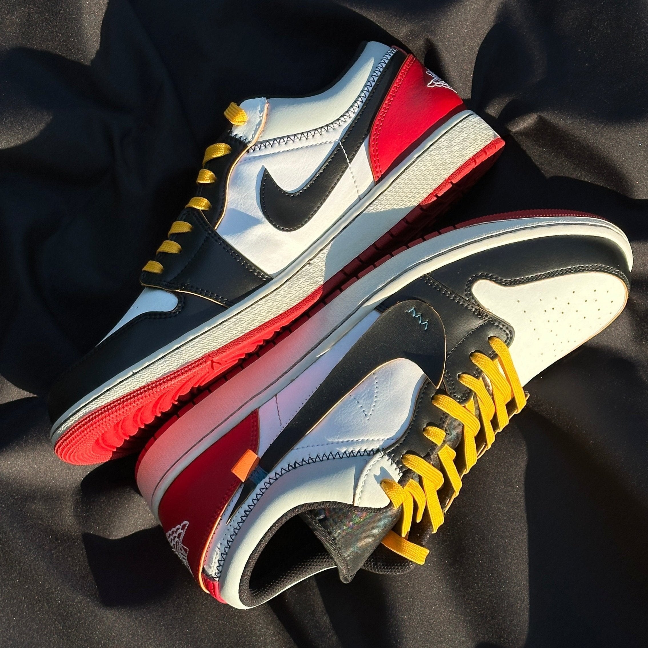 Colorful low-top sneakers with black, red, white panels and yellow laces on black fabric