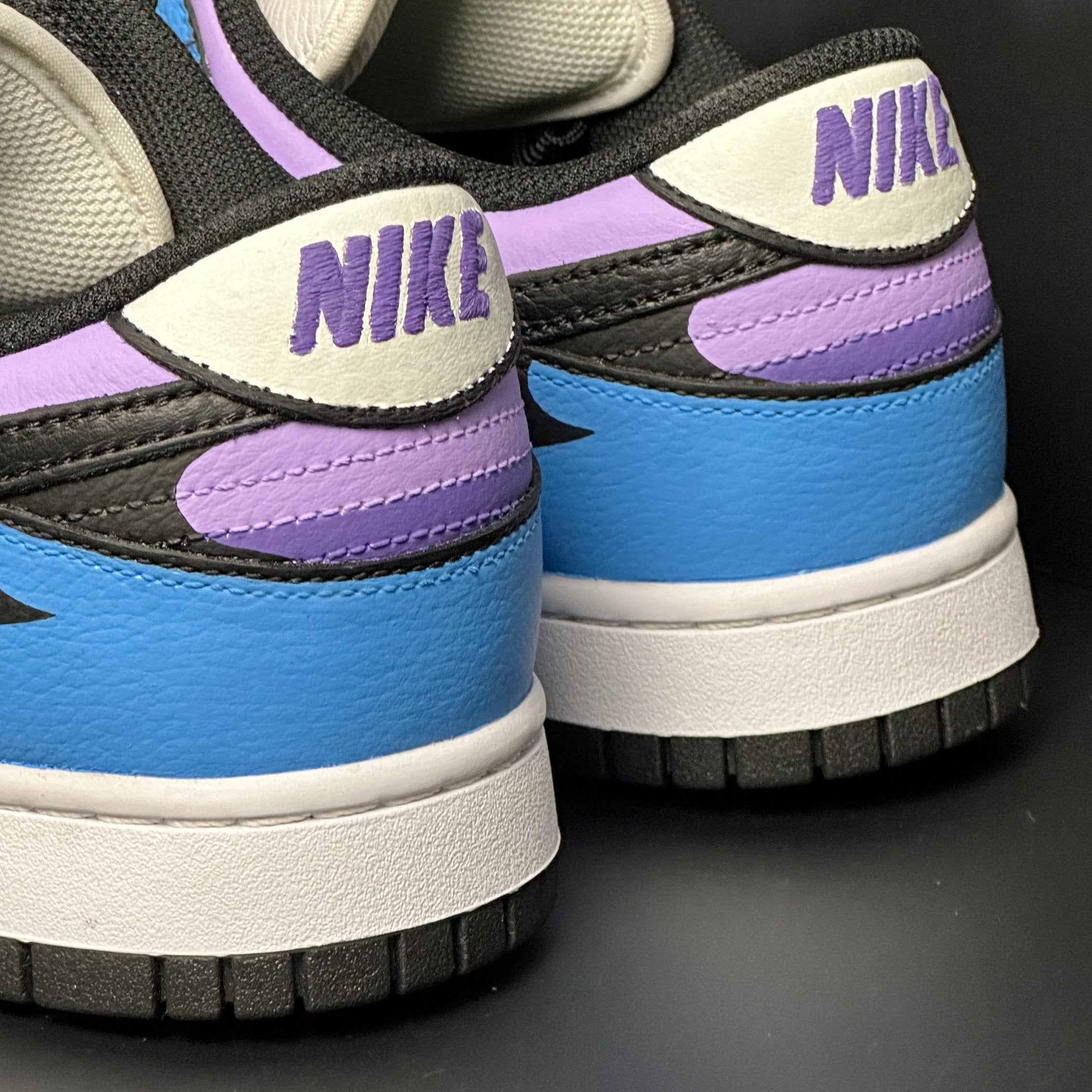 Close-up of Nike Dunk sneakers in blue, purple, black and white on a dark background