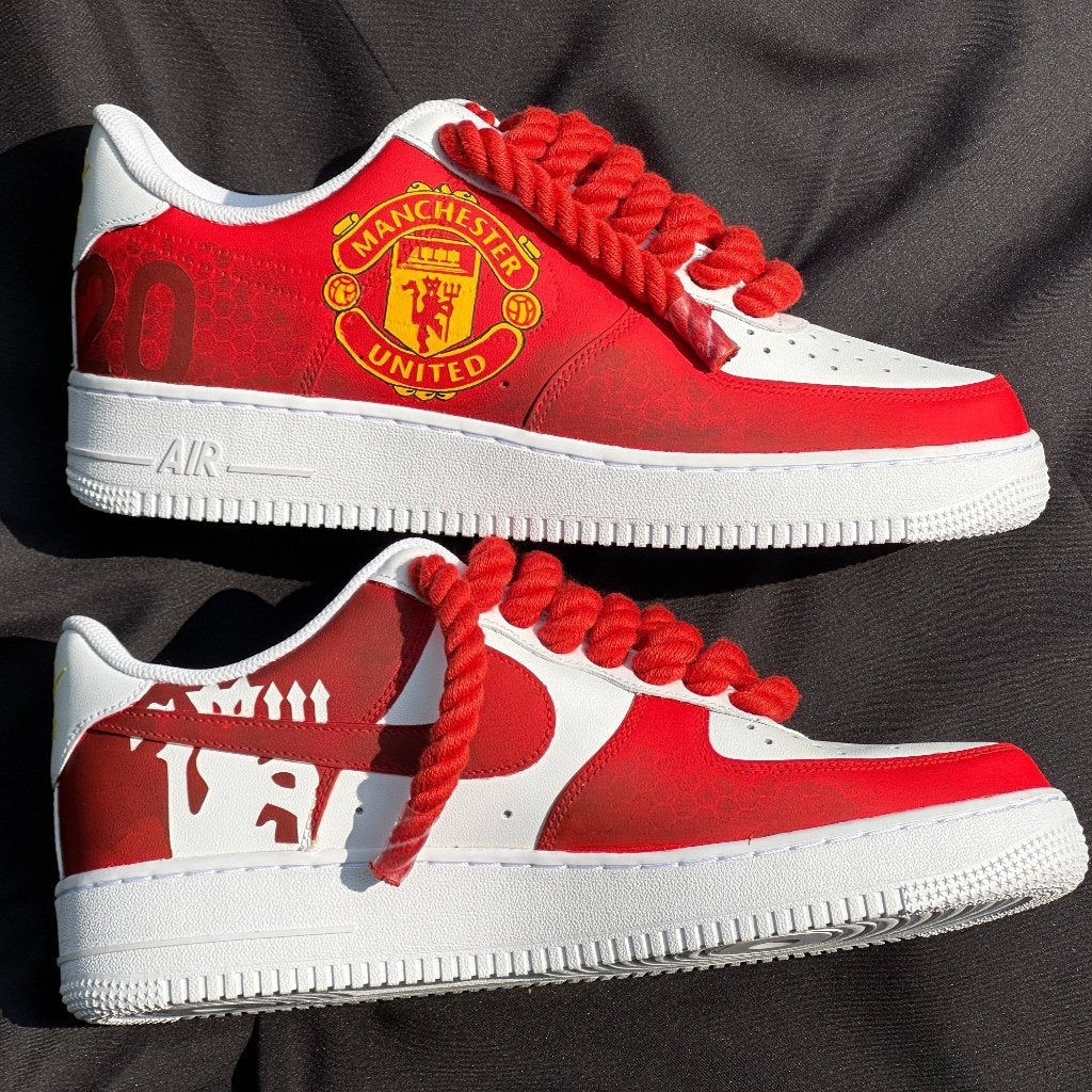 Custom red and white sneakers with Manchester United logo and bold red laces on black fabric.