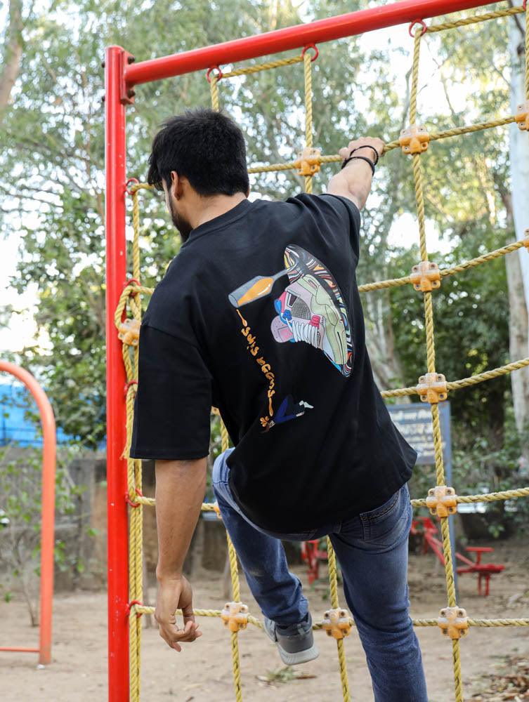 Man in streetwear graphic t-shirt and jeans climbing yellow rope net outdoors