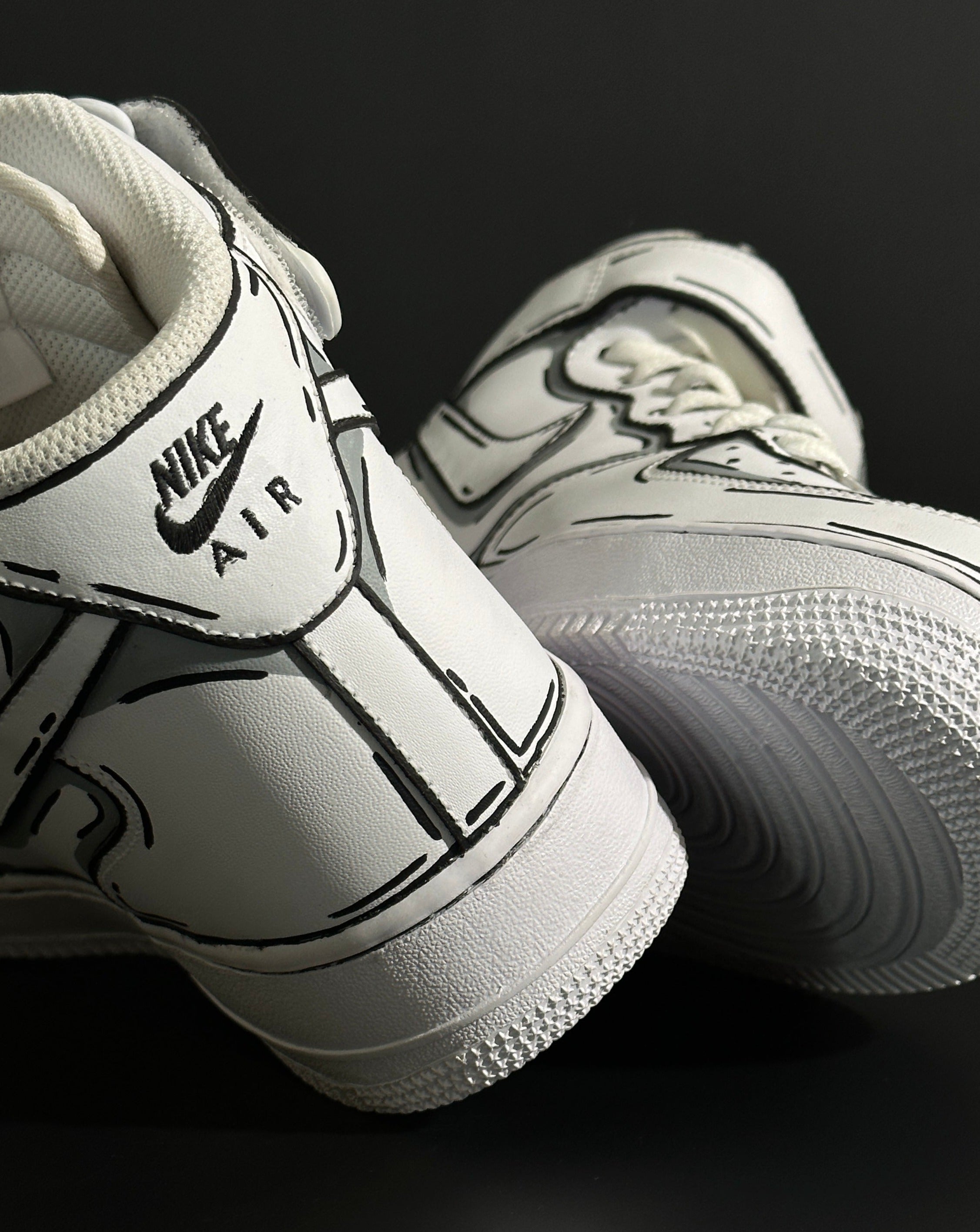 White Nike Air Force 1 sneakers with black outline details on a dark background