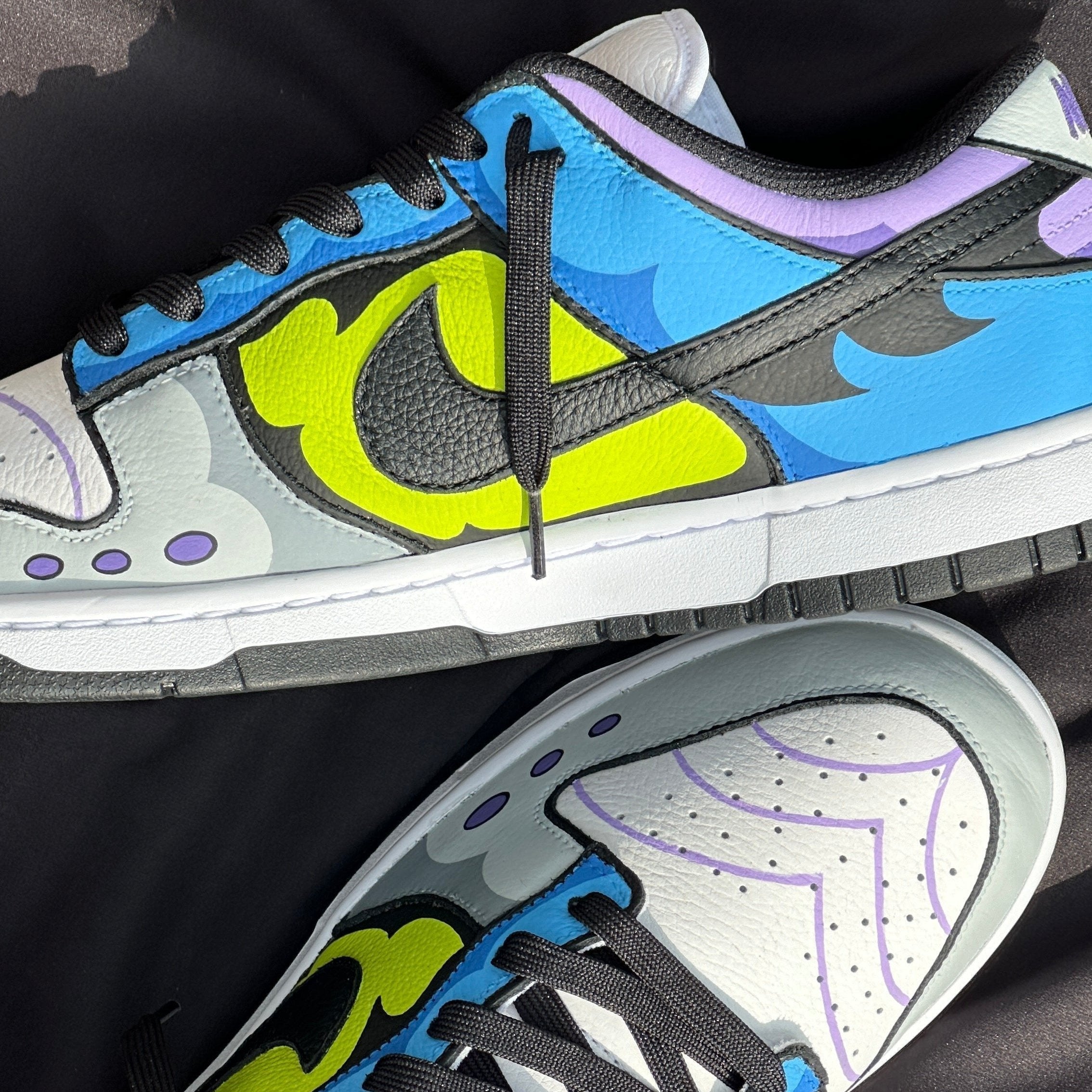 Colorful designer sneakers with vibrant blue, yellow, purple accents and black laces on black fabric