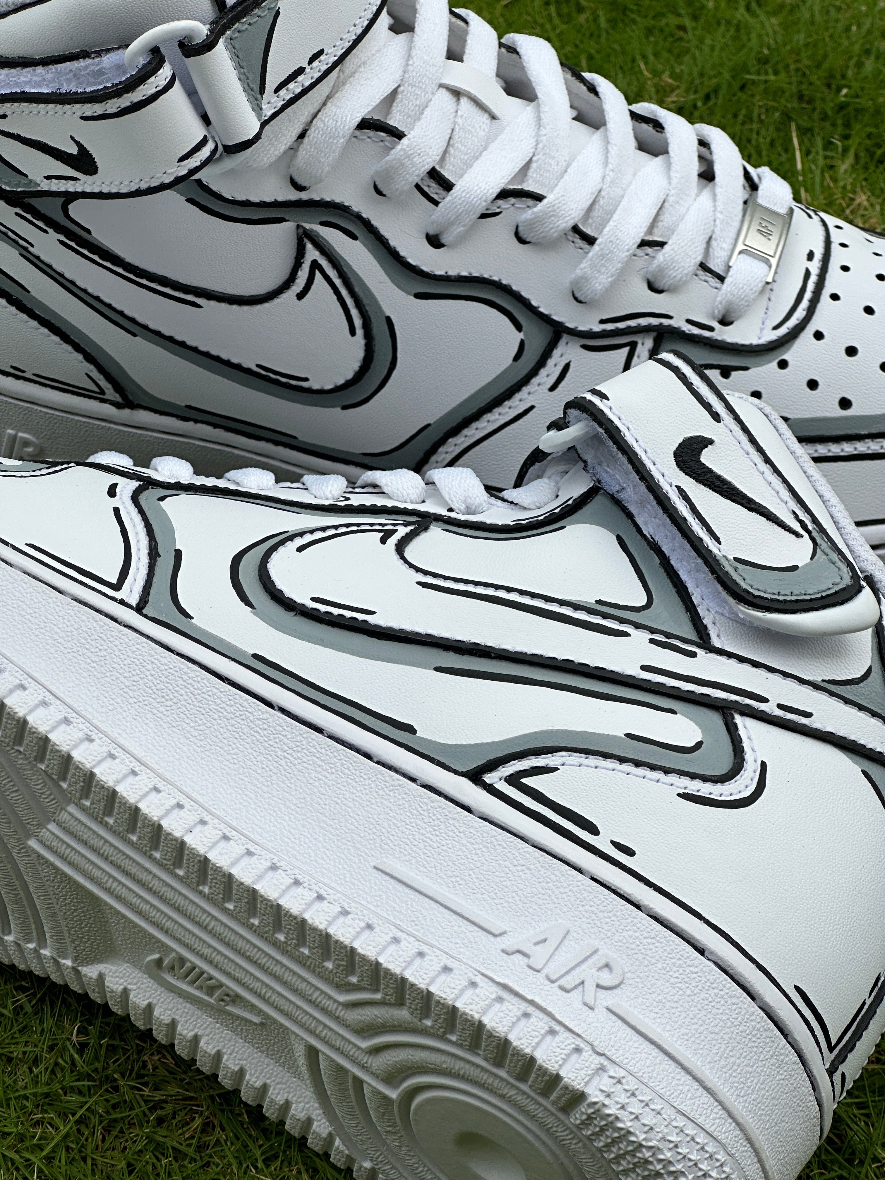 White leather streetwear sneakers with bold black outlined details on grass