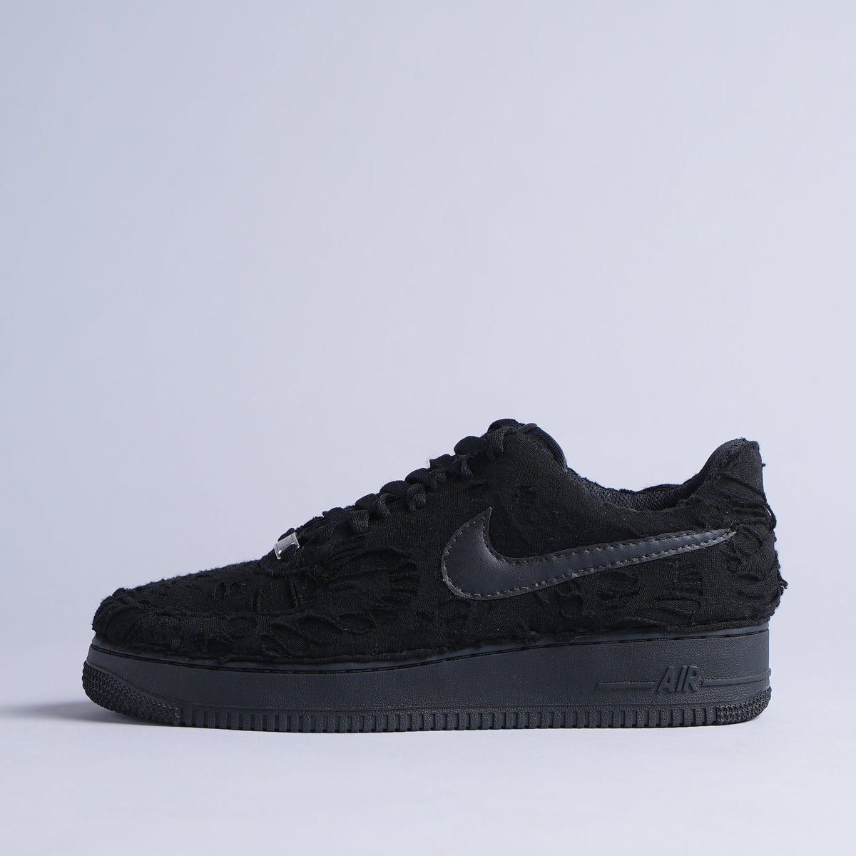 Black Nike Air Force 1 sneaker with textured floral upper on white background