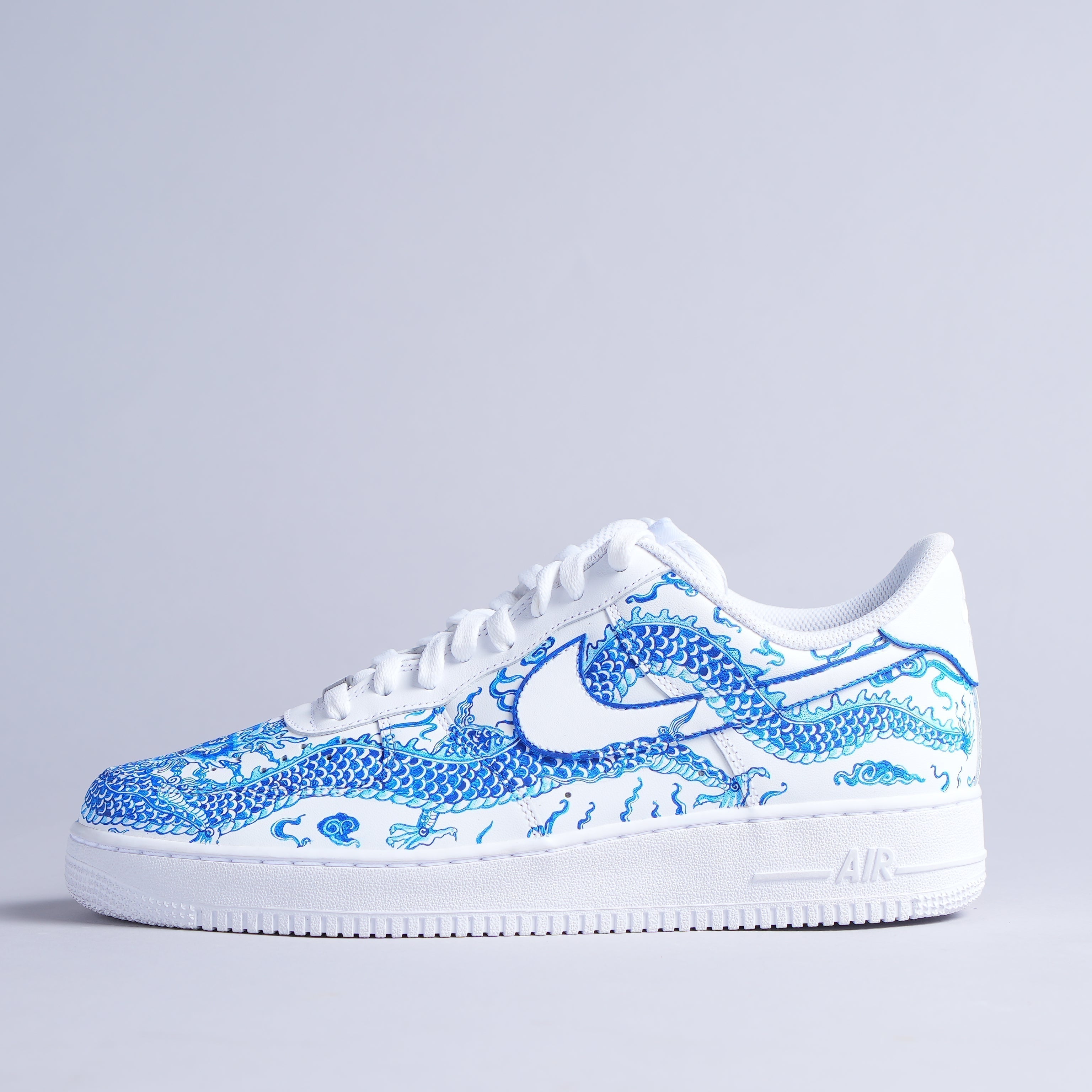 White sneaker with blue dragon graphic, streetwear-inspired, designer footwear