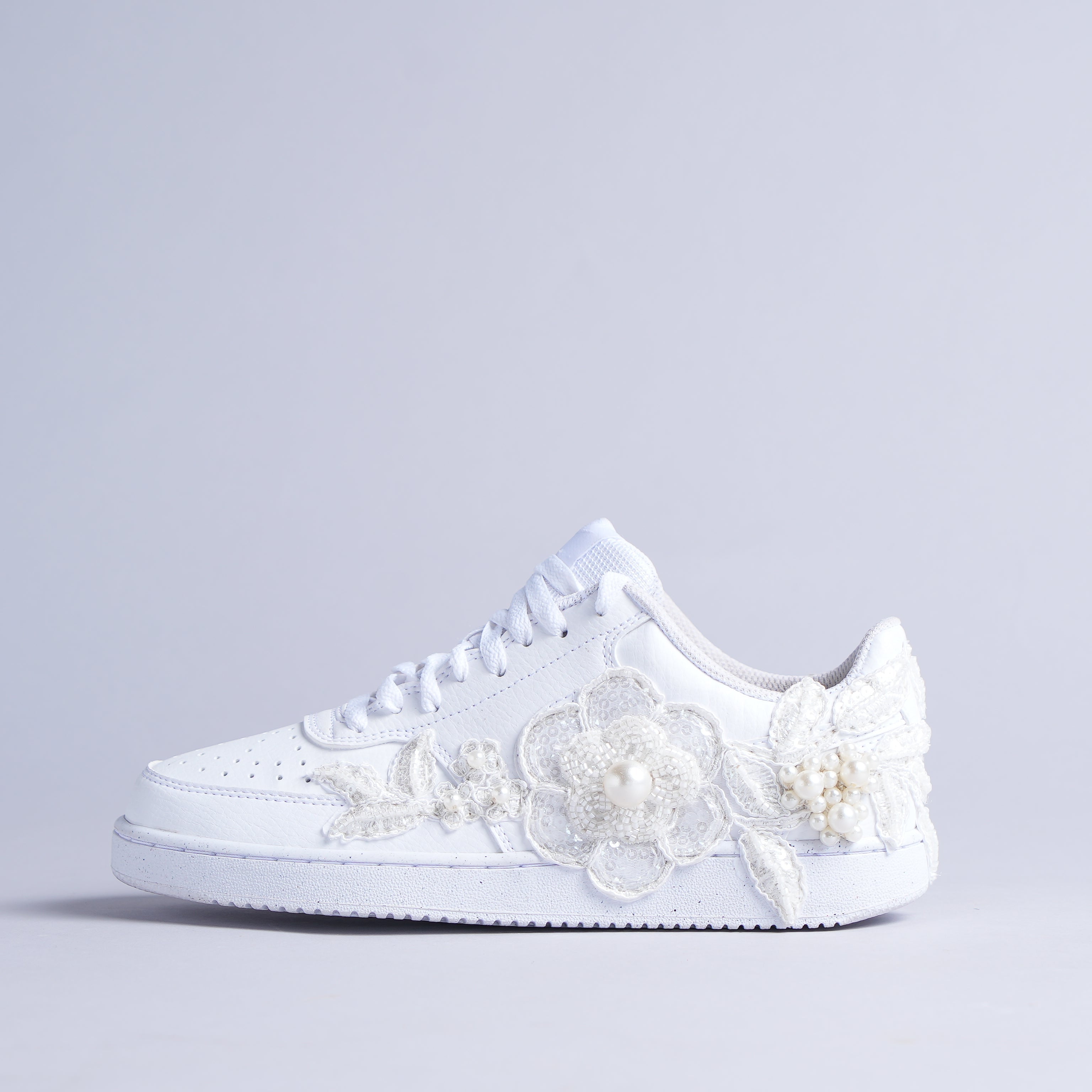 White low-top sneaker with pearl and floral lace embroidery, streetwear style on light background
