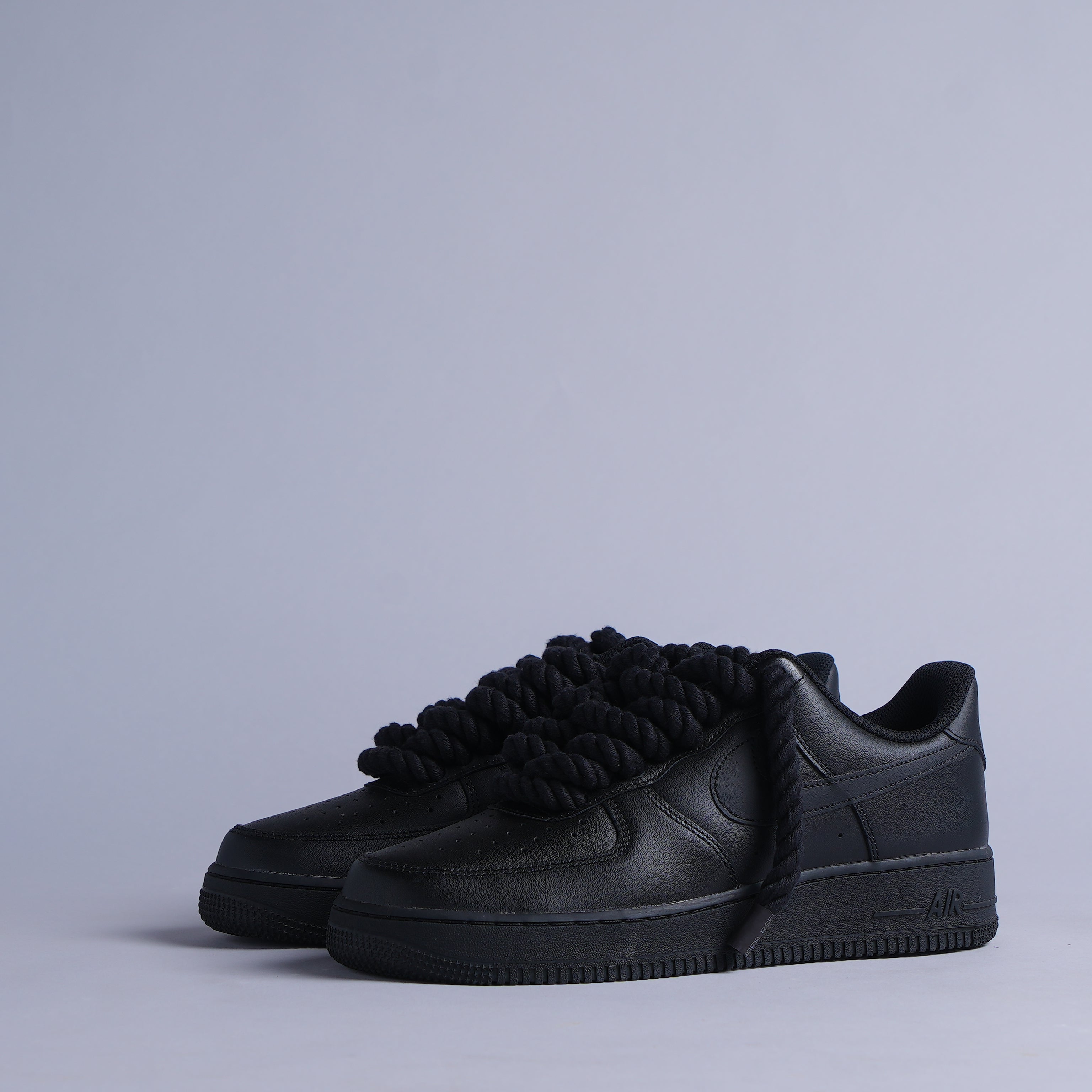 Black leather sneakers with thick rope laces on a plain background, streetwear shoes