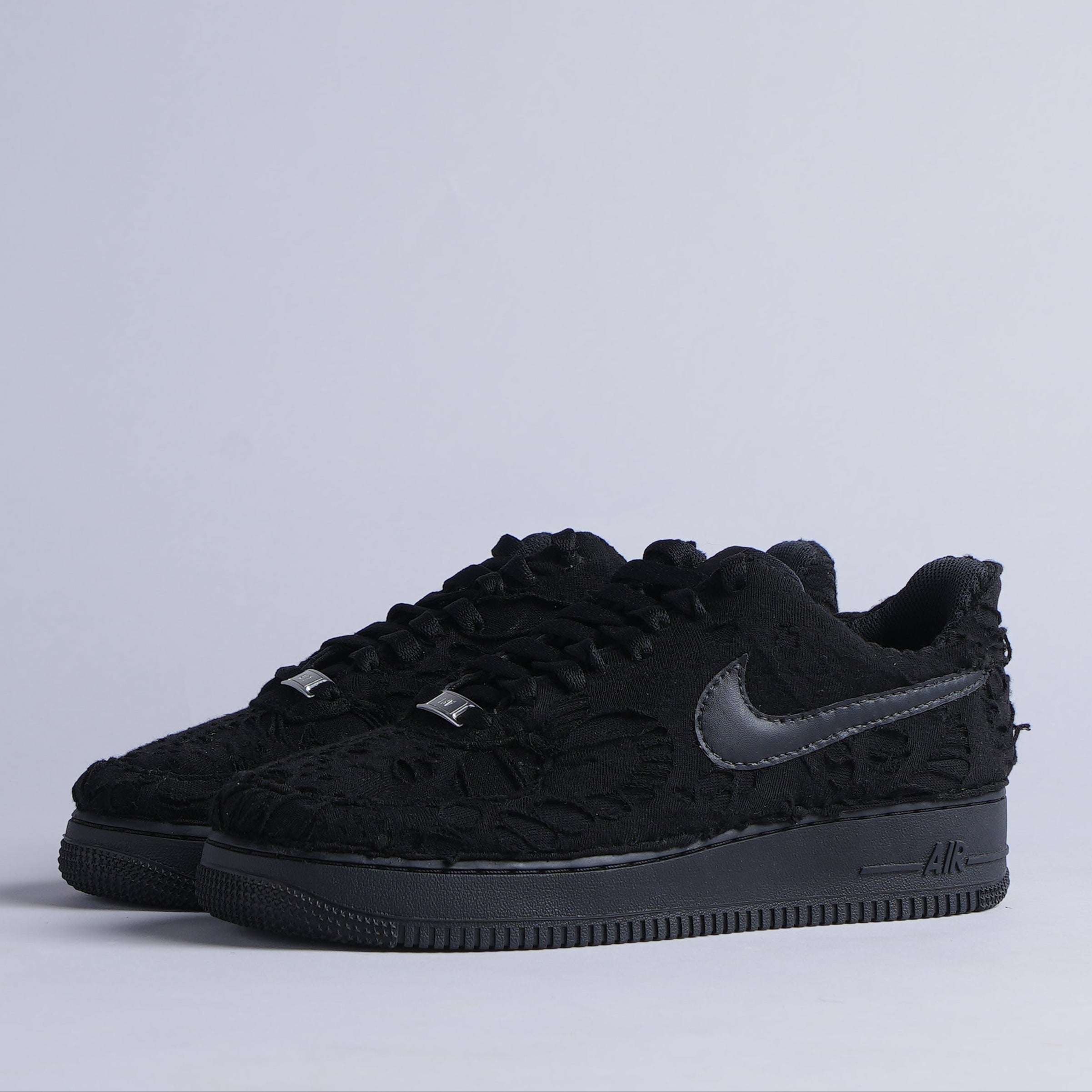 Black Nike low-top sneakers with textured floral pattern and leather Swoosh, streetwear style