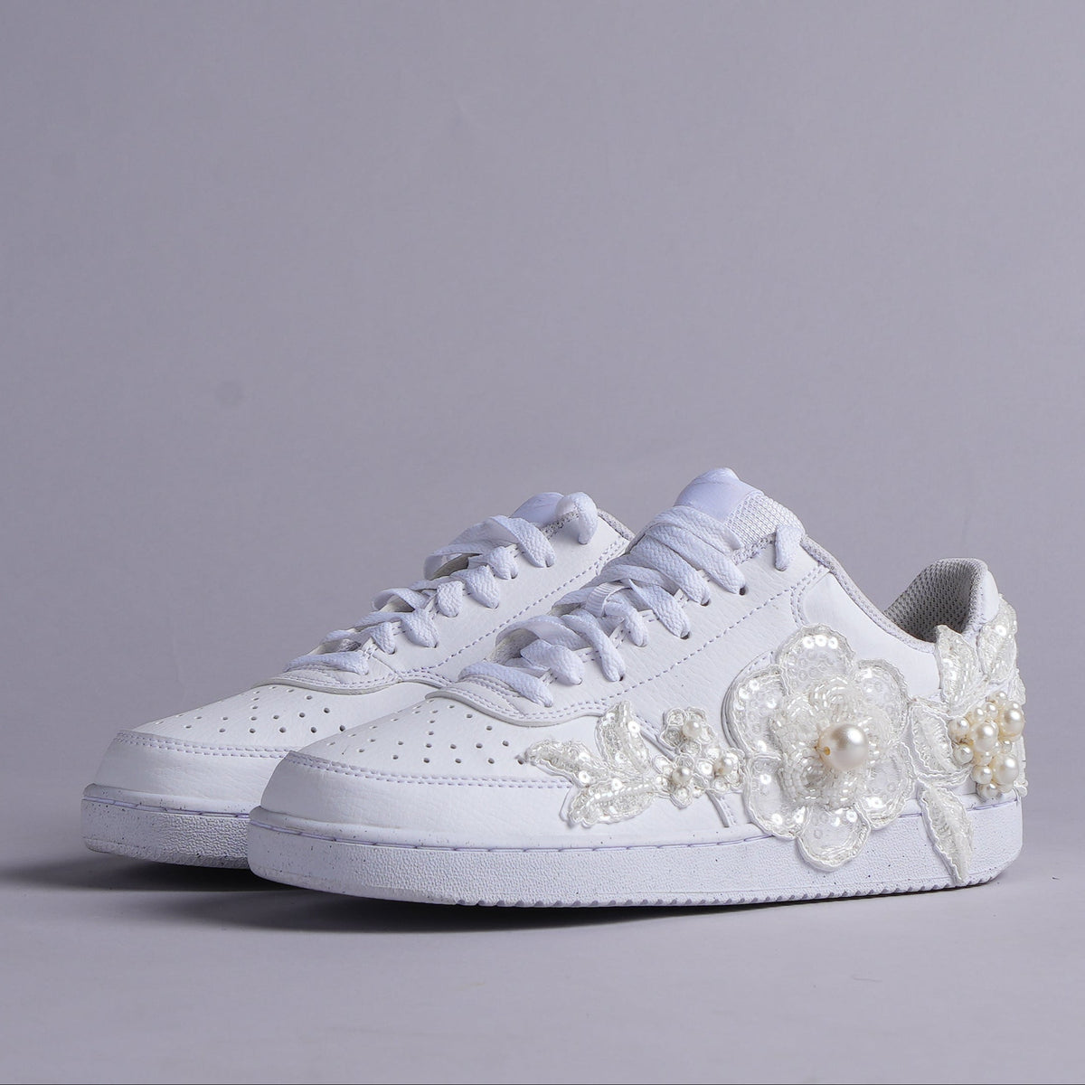 White low top sneakers with floral lace and pearl embellishments, streetwear style