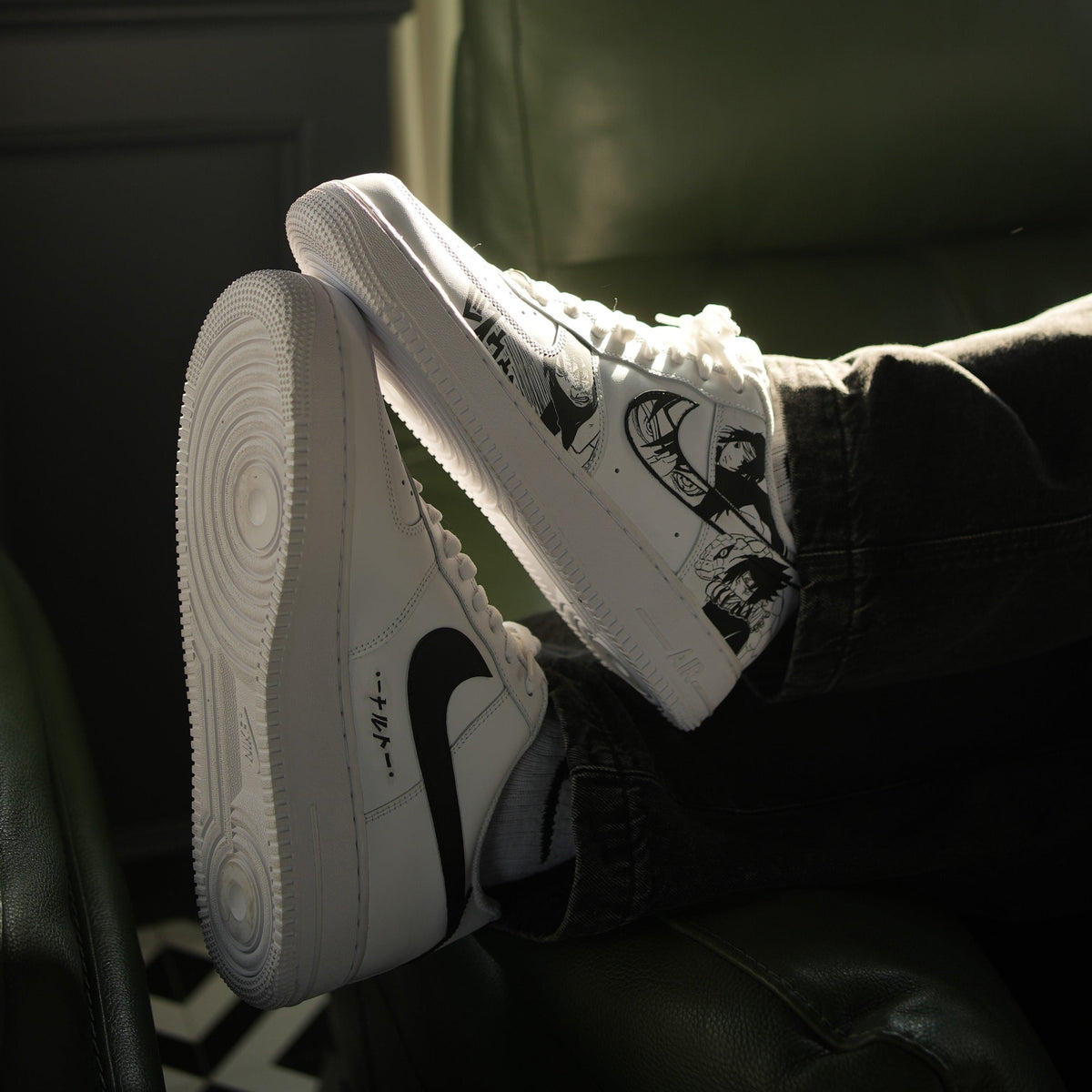White streetwear sneakers with black graphic design and black swoosh, worn with dark pants