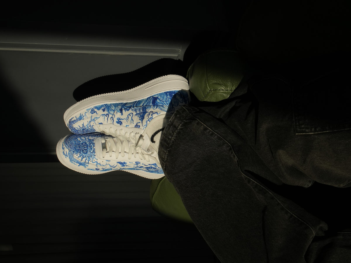 White streetwear sneakers with blue art pattern worn with dark jeans, luxury footwear style