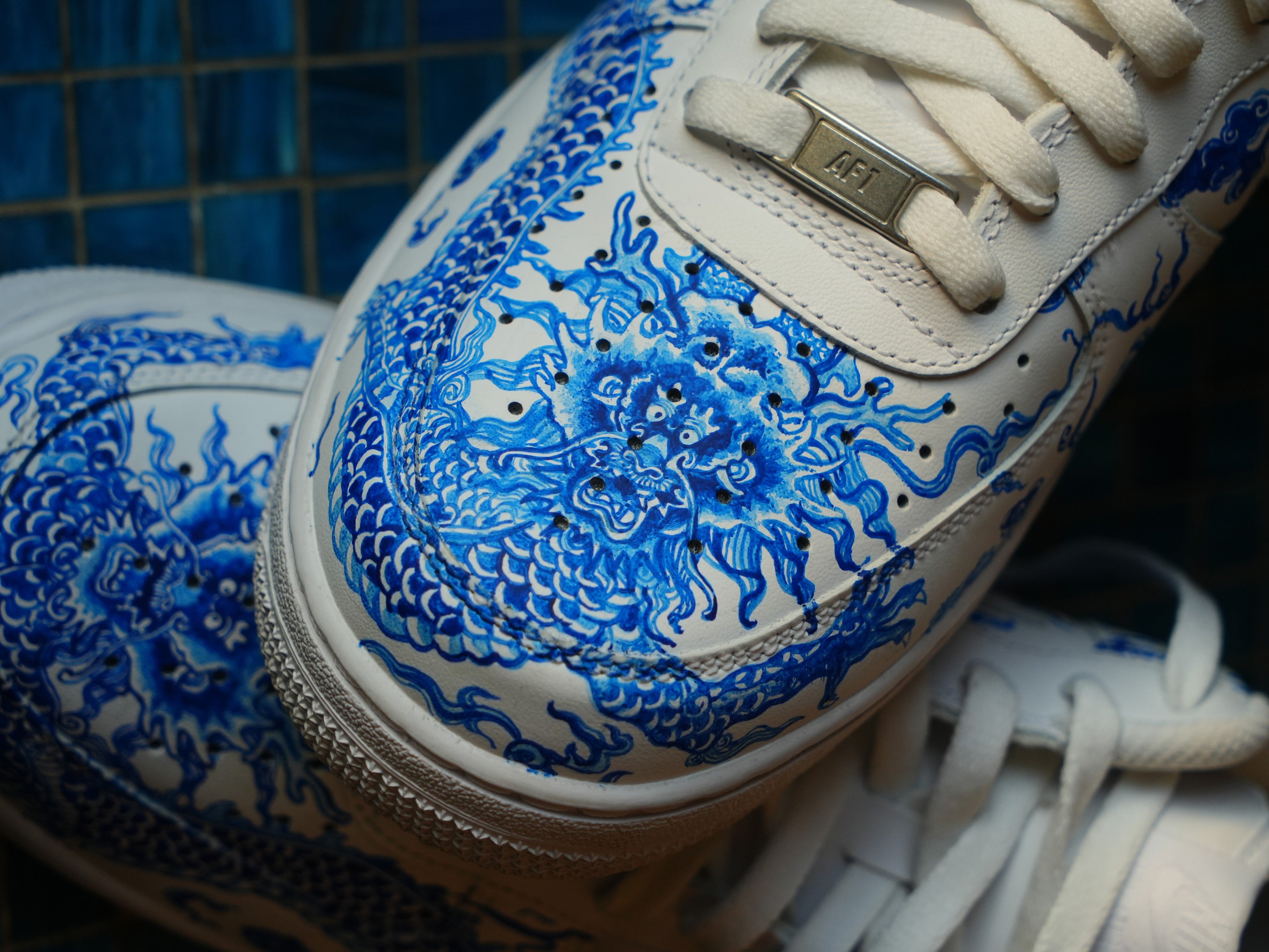 White sneaker with detailed blue dragon design, luxury streetwear footwear