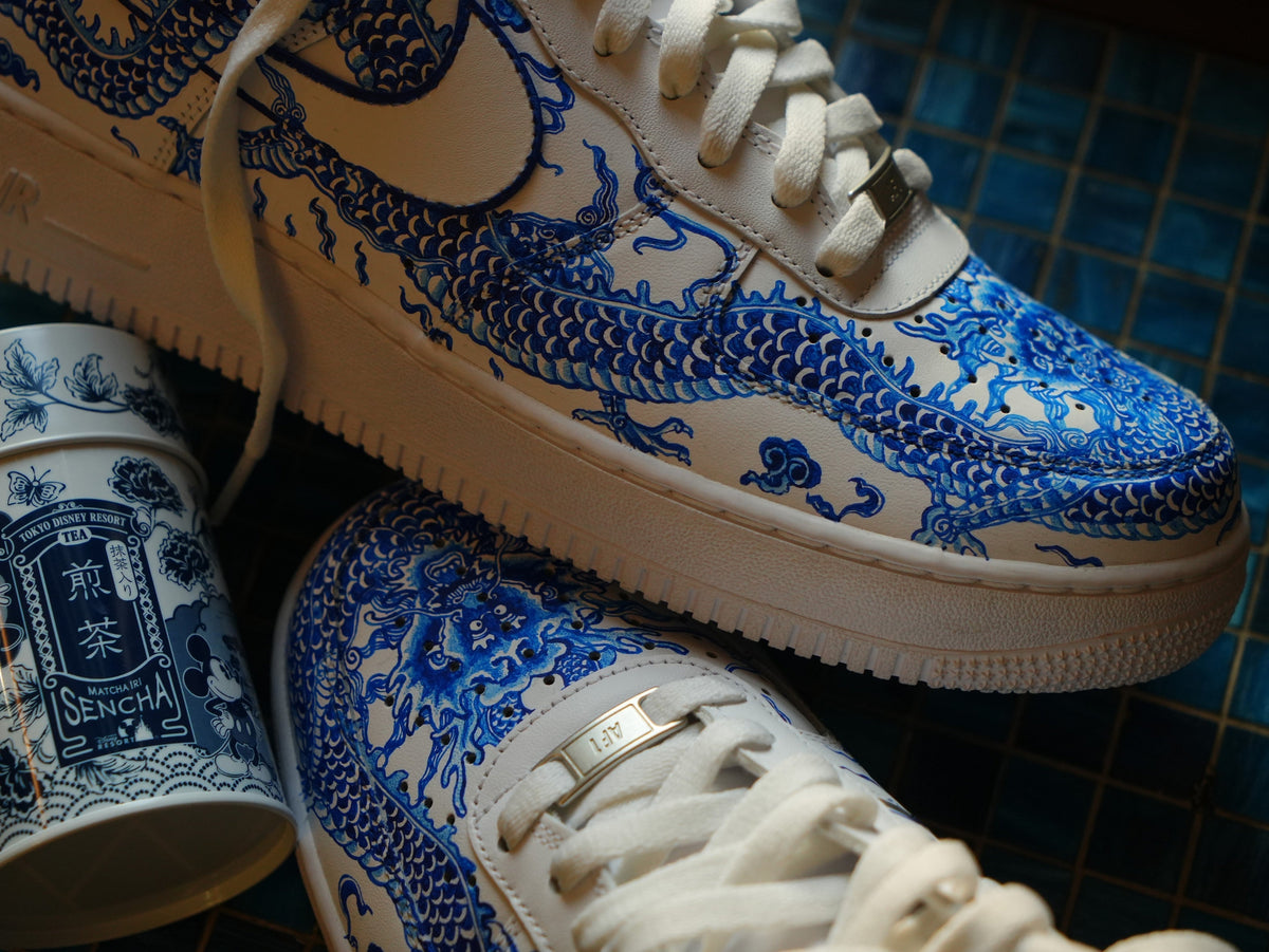 White sneakers with blue dragon graphic, designer streetwear shoes on tiled surface
