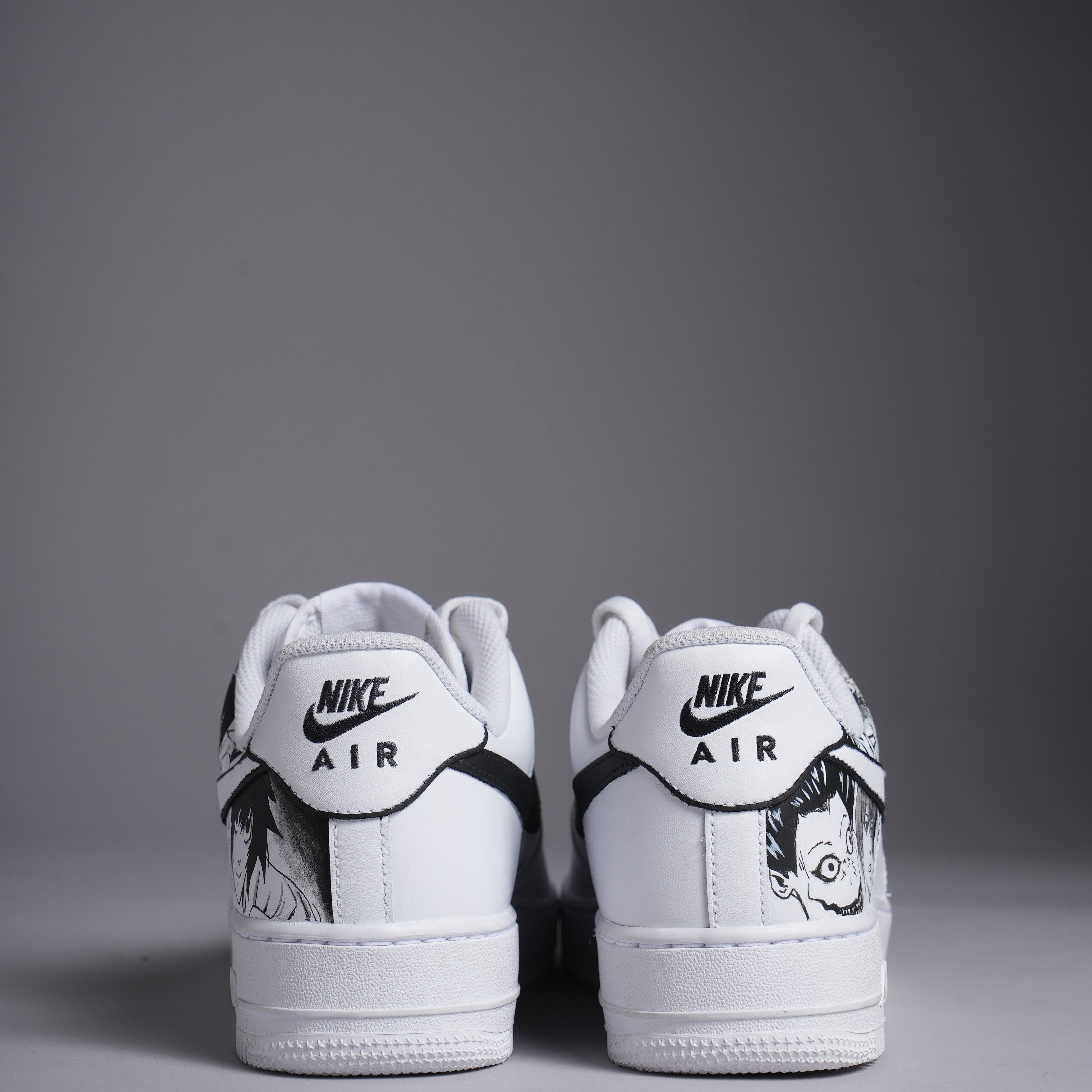 White Nike Air Force 1 sneakers with black graphic art on heels, streetwear sneakers