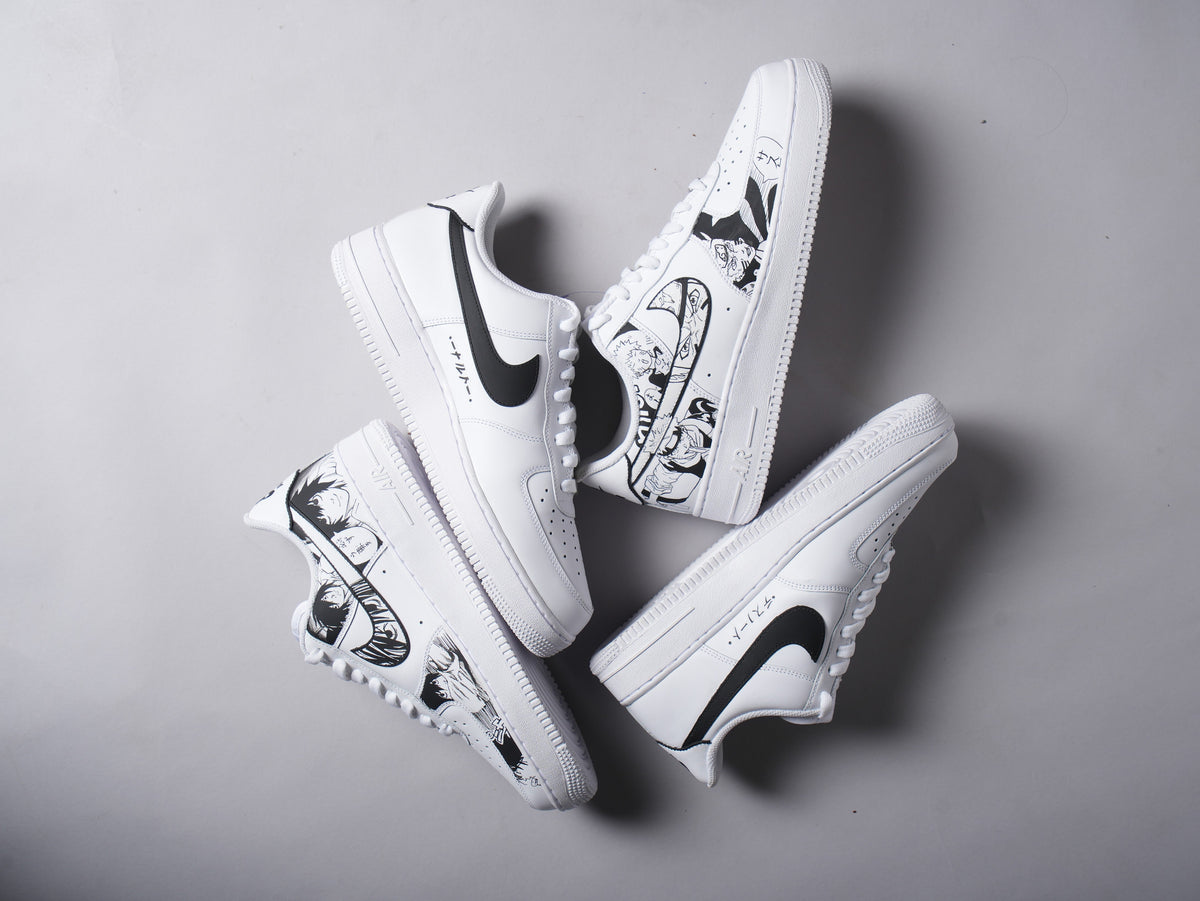 White streetwear sneakers with black anime-style artwork and black Nike swoosh on grey background