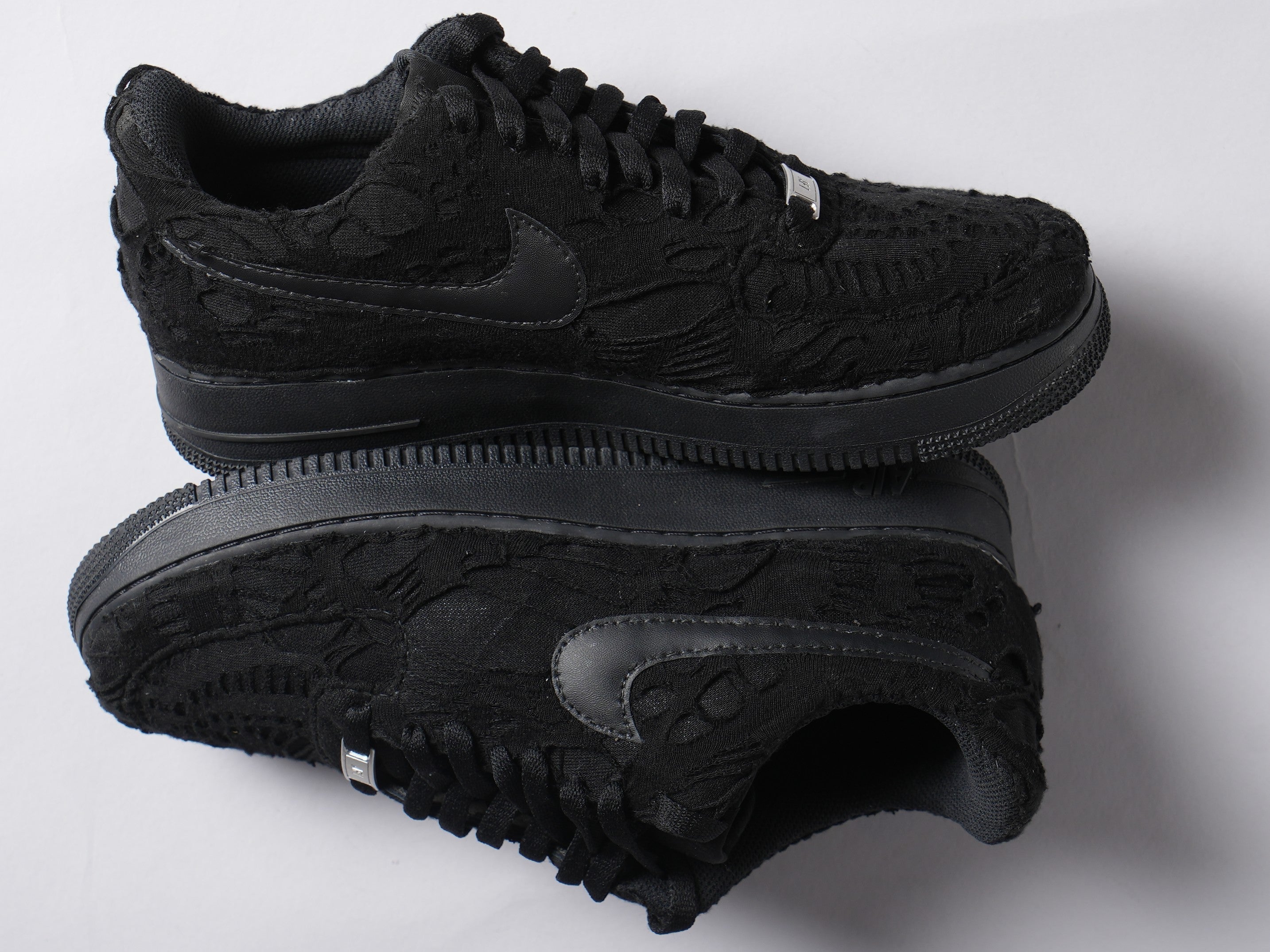 Black low-top streetwear sneakers with textured suede and tonal Nike Swoosh logo