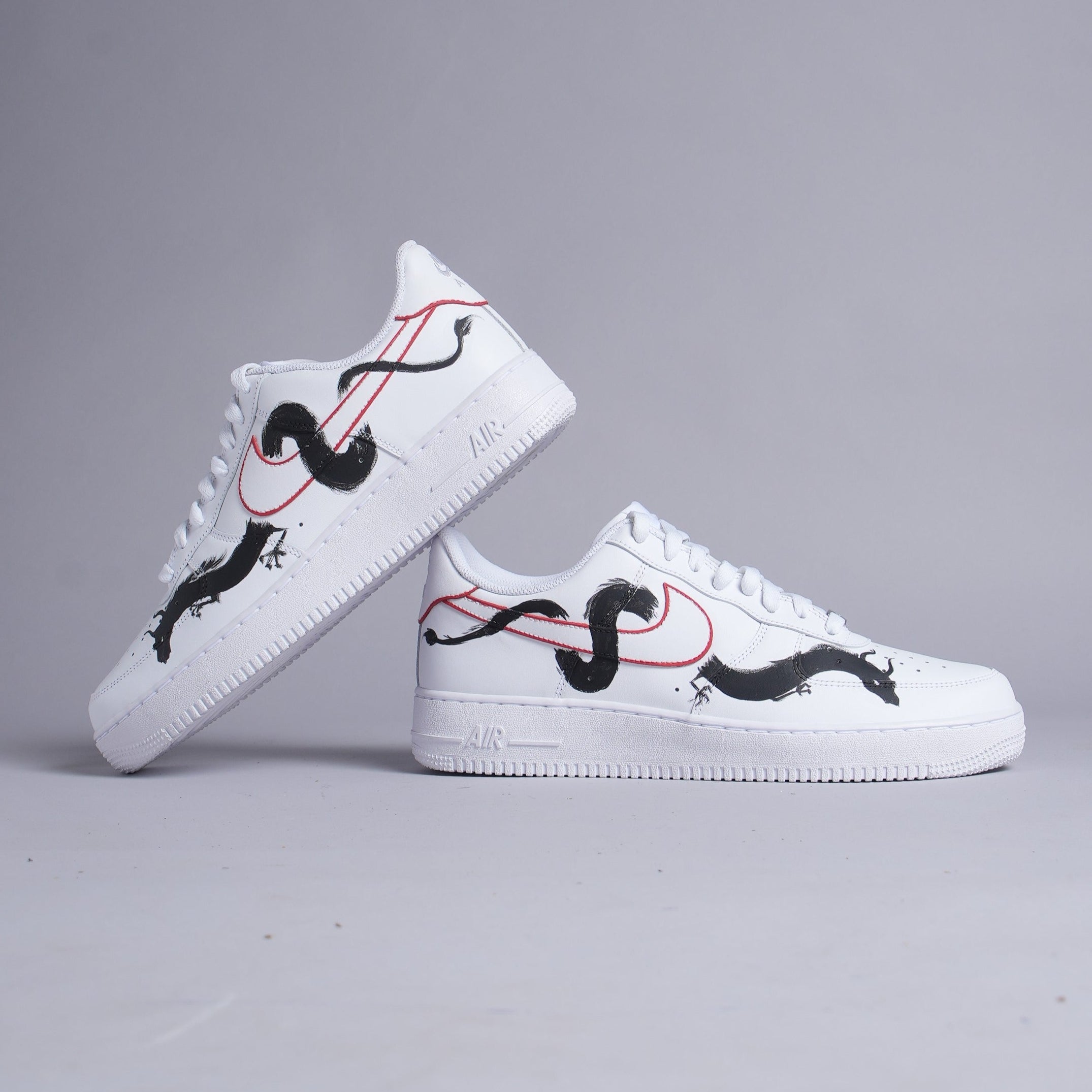 White streetwear sneakers with black dragon and red outline design on gray background