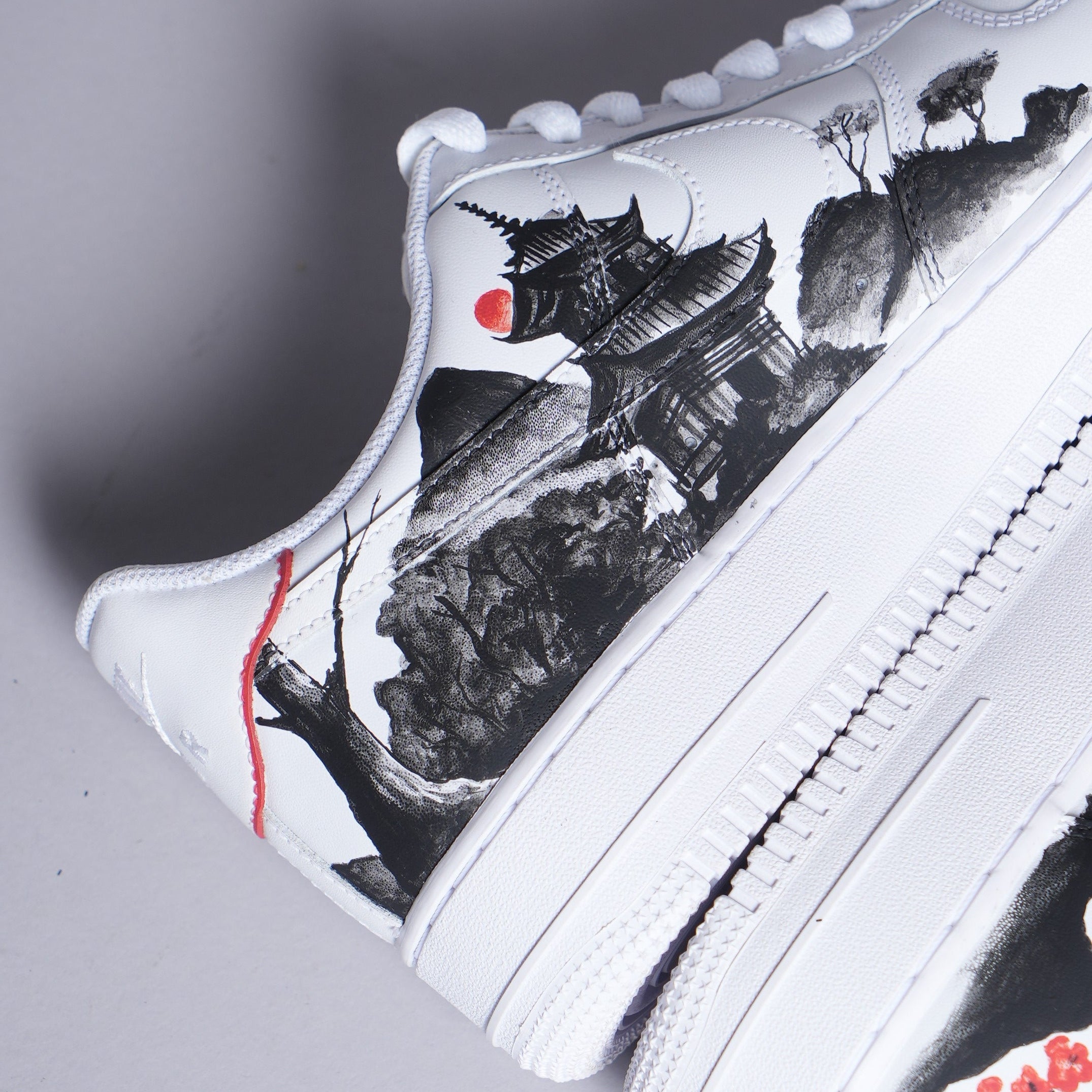White sneaker with black and red Japanese temple artwork and mountain landscape design