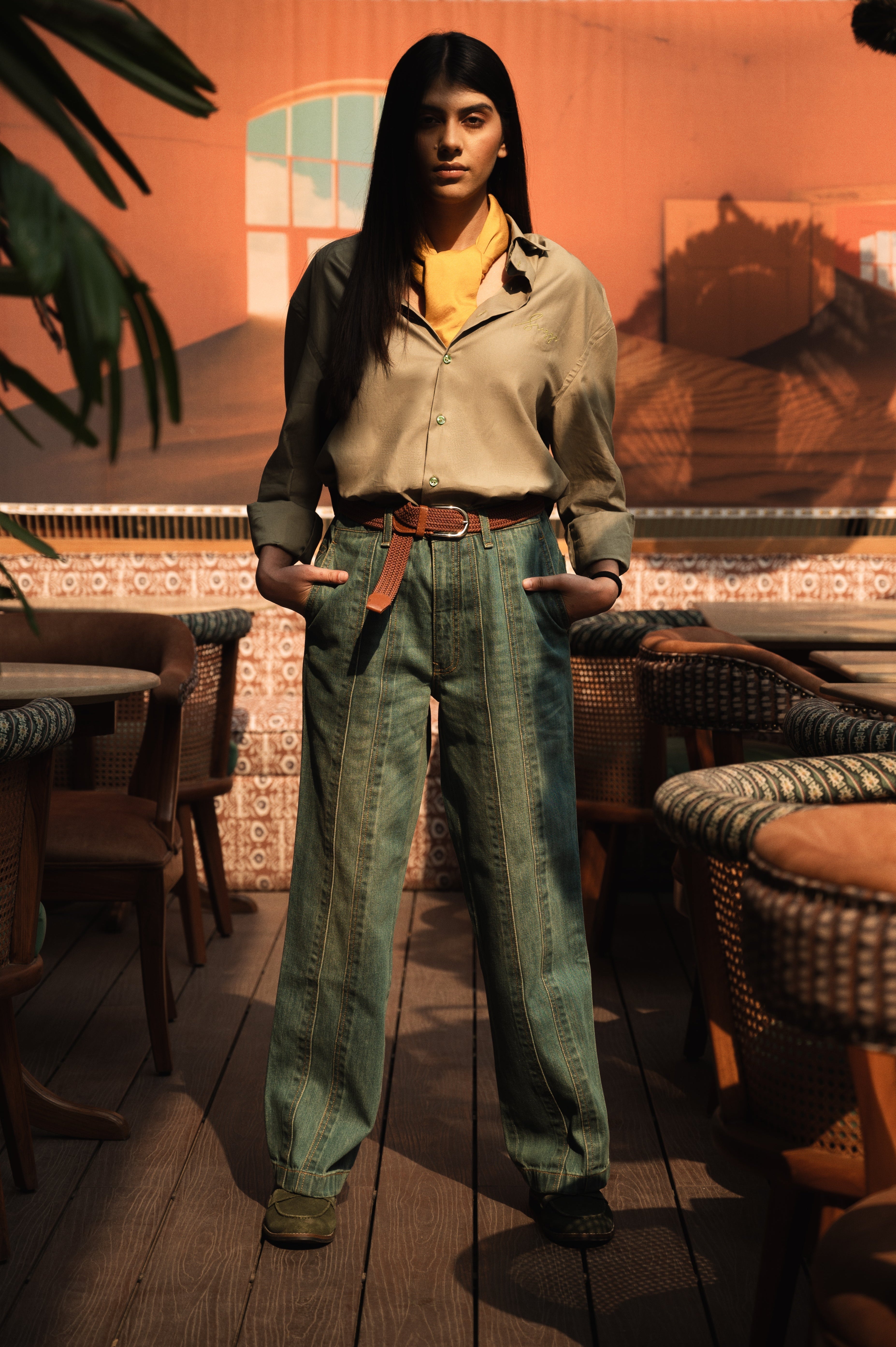 Woman in oversized shirt and wide-leg jeans, streetwear style, indoor cafe setting