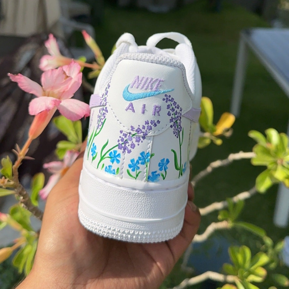 Custom white Nike Air shoe with hand-painted purple and blue floral design outdoors