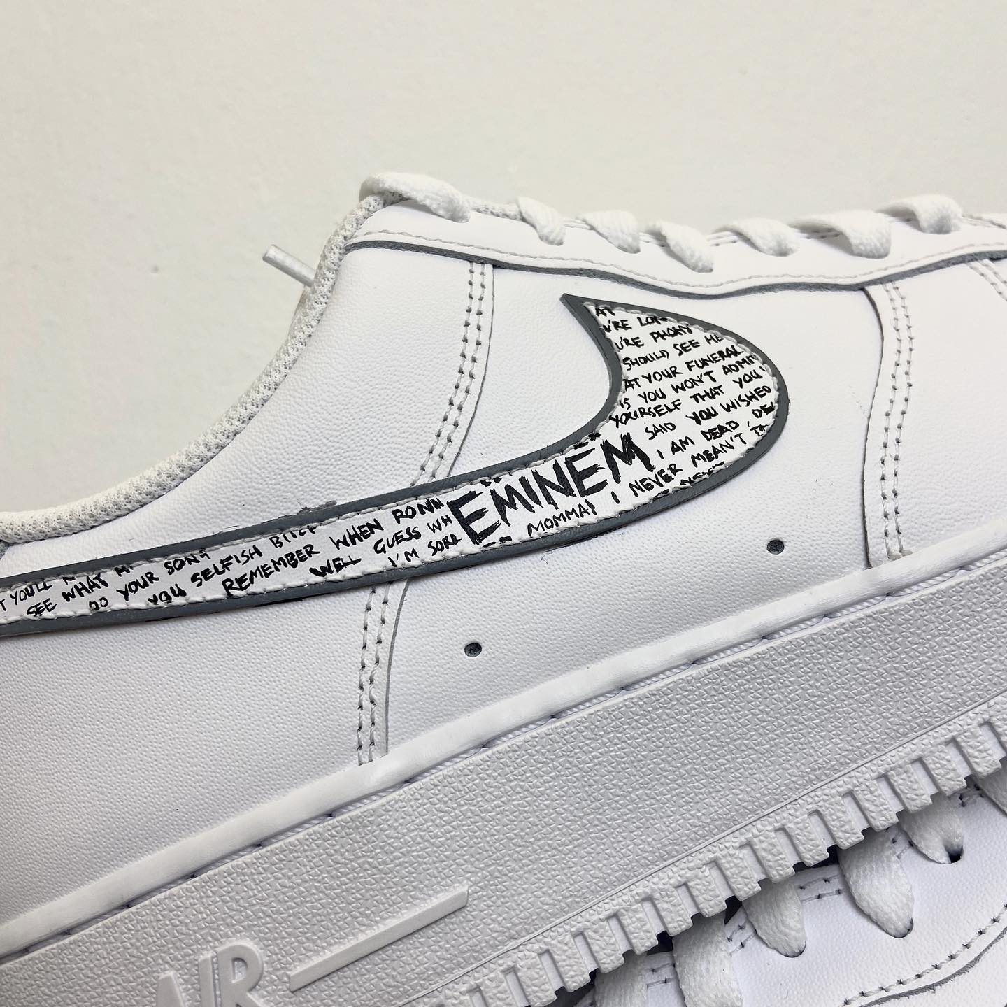 White custom Air Force 1 sneaker with Eminem lyrics design on Swoosh, streetwear style