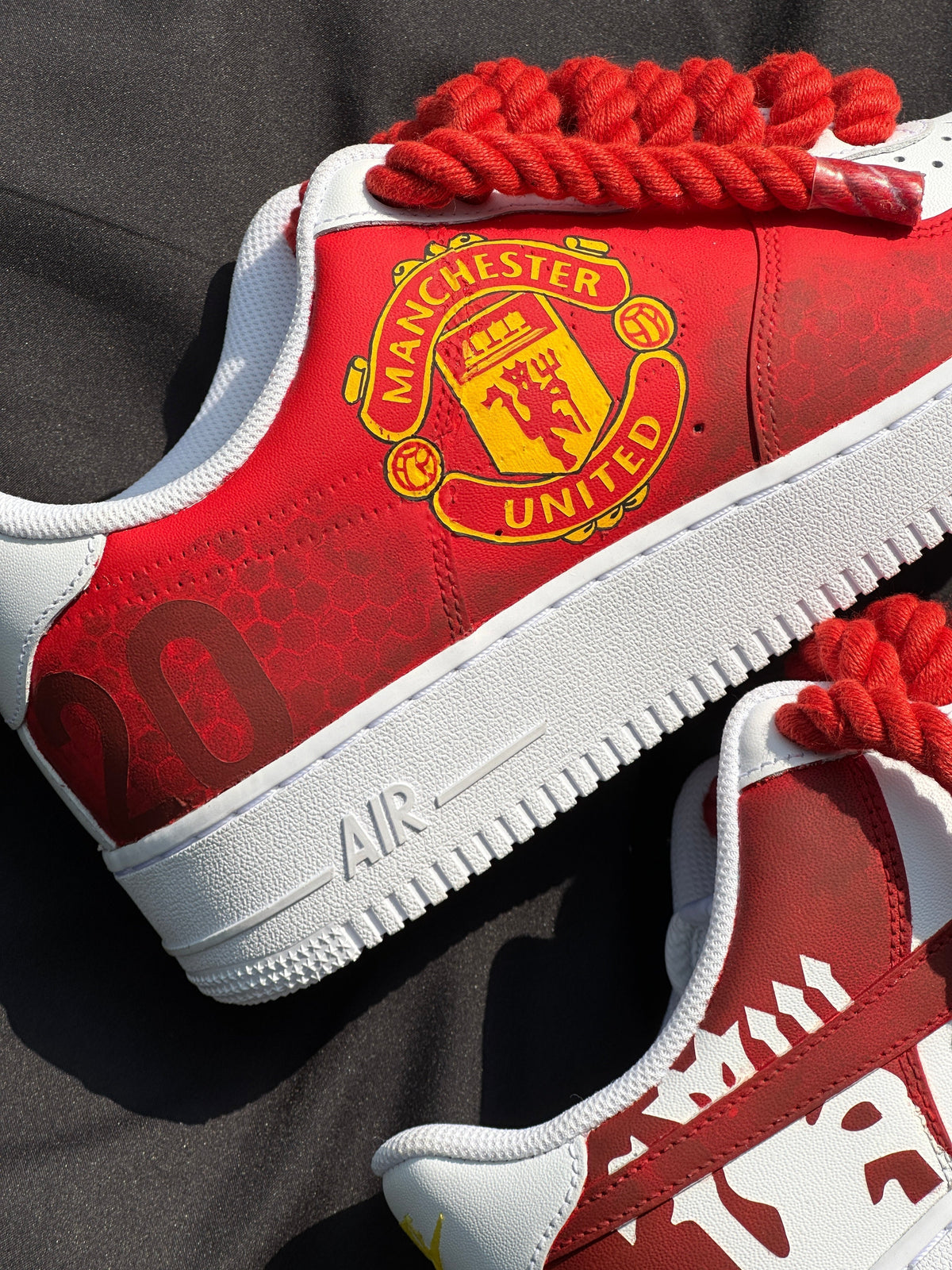 Red and white Manchester United custom sneakers with bold logo and rope-style red laces