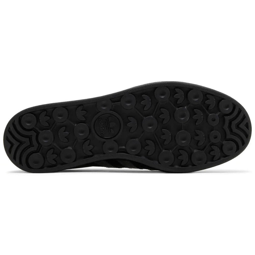 Black Adidas sneaker outsole with textured grip and trefoil logo, streetwear footwear