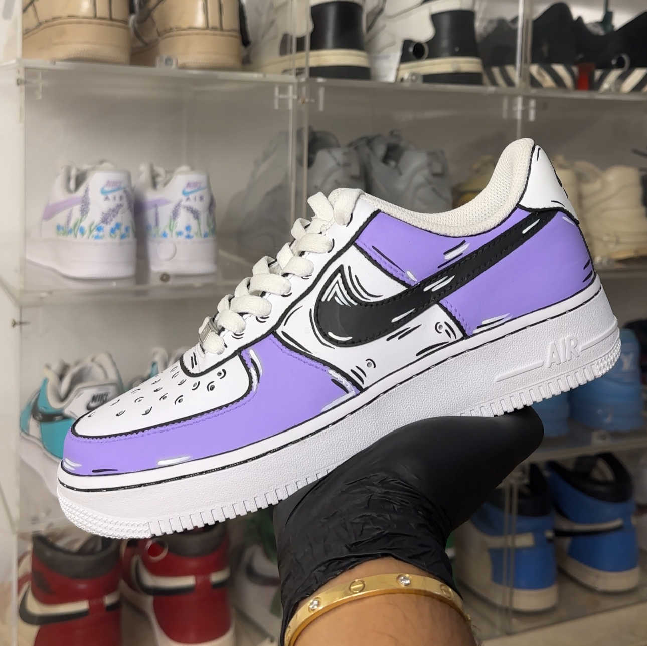 Hand holding a custom purple and white Nike Air Force 1 sneaker with cartoon-style detailing.