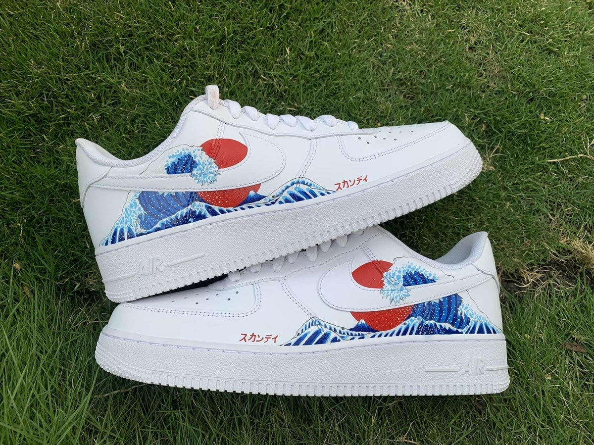 White streetwear sneakers with blue wave and red sun graphic detail on grass