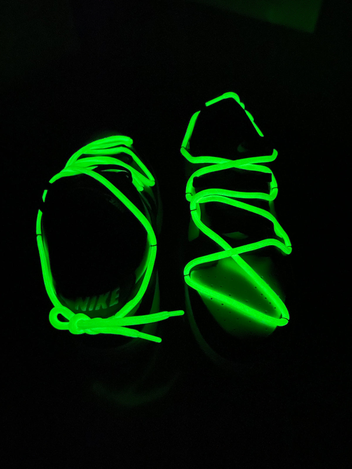 Pair of Nike sneakers with glowing green shoelaces in the dark, streetwear footwear