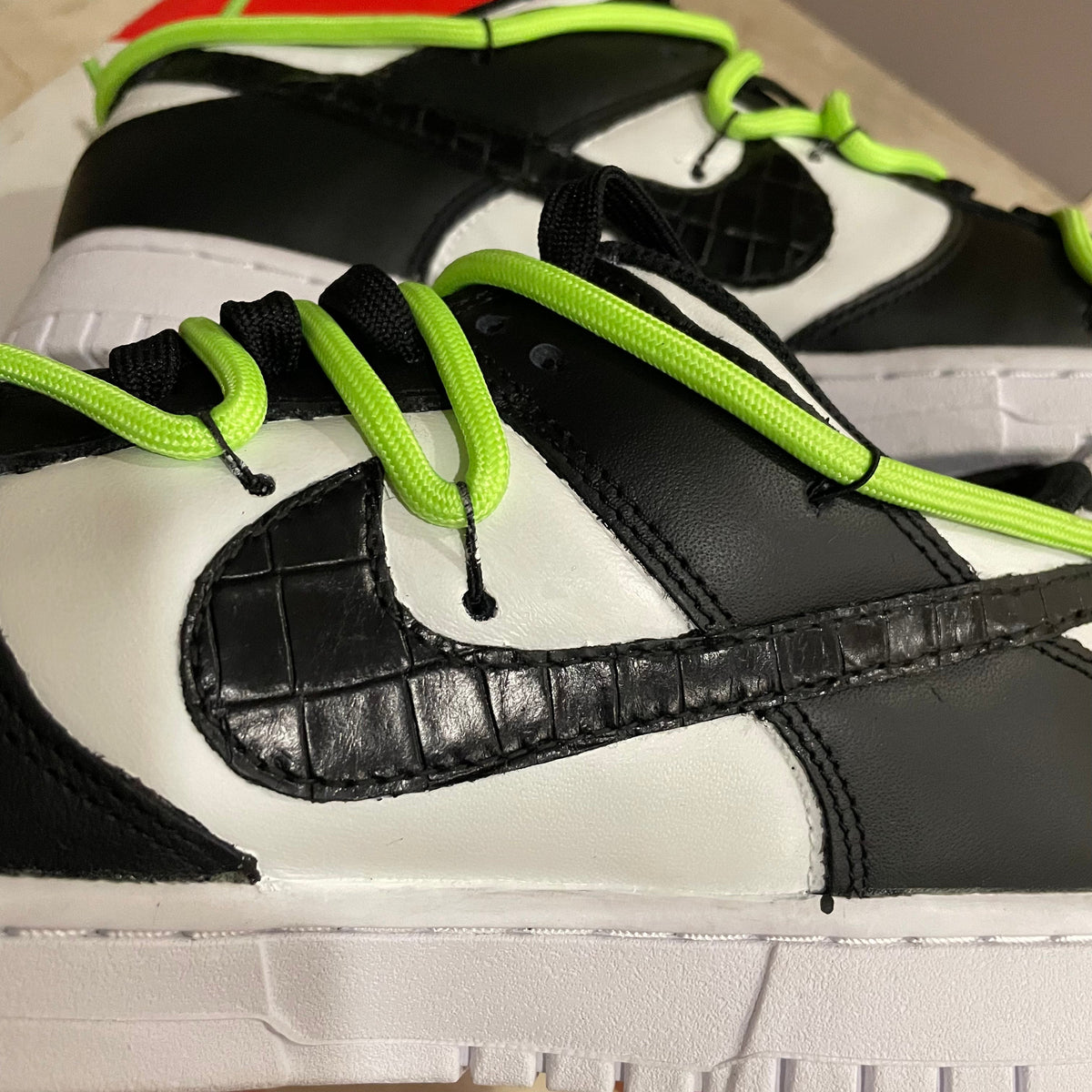 Close-up of black and white sneaker with textured leather swoosh and neon green laces