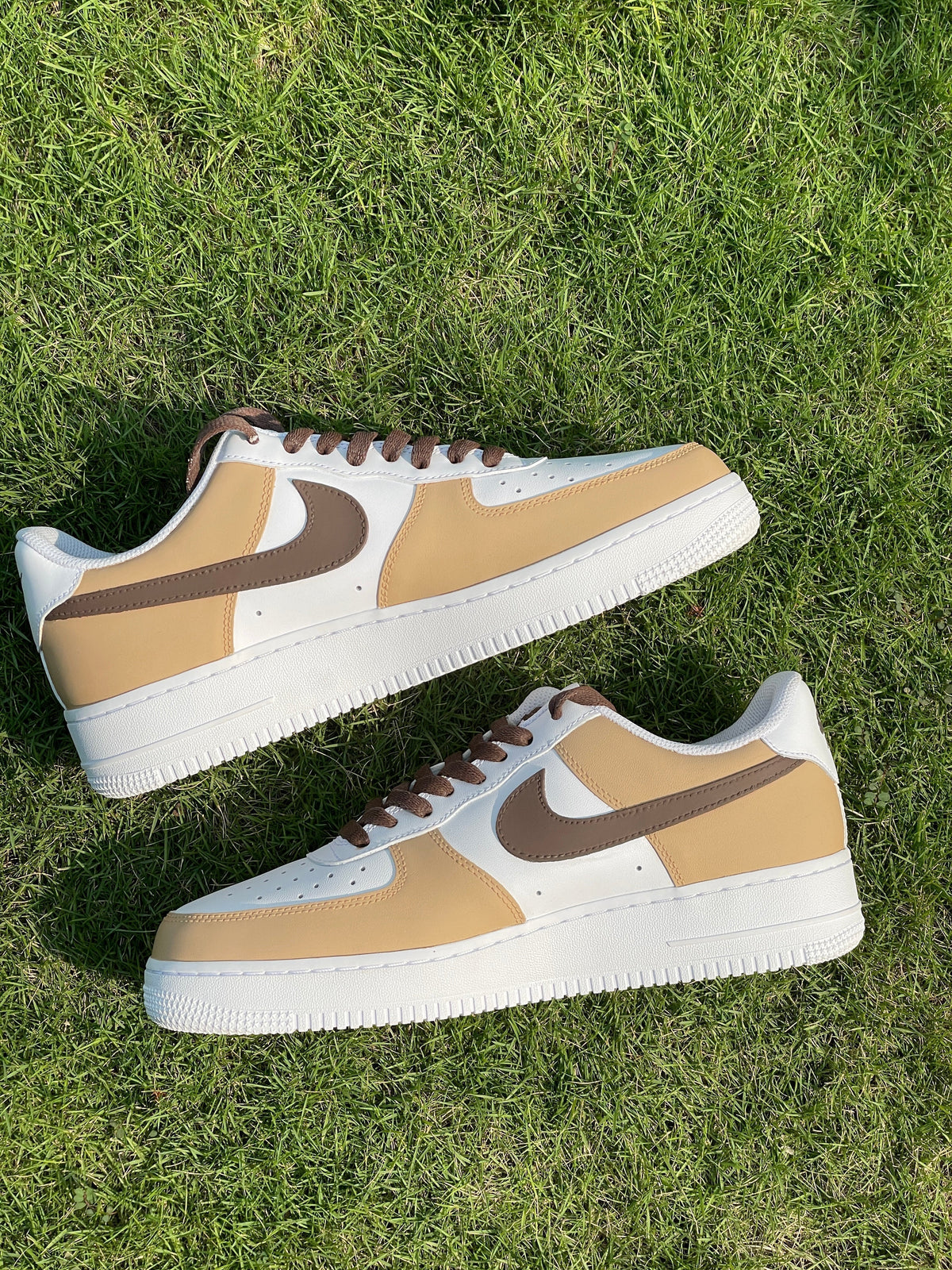Tan and white Nike sneakers with brown swoosh and laces on green grass
