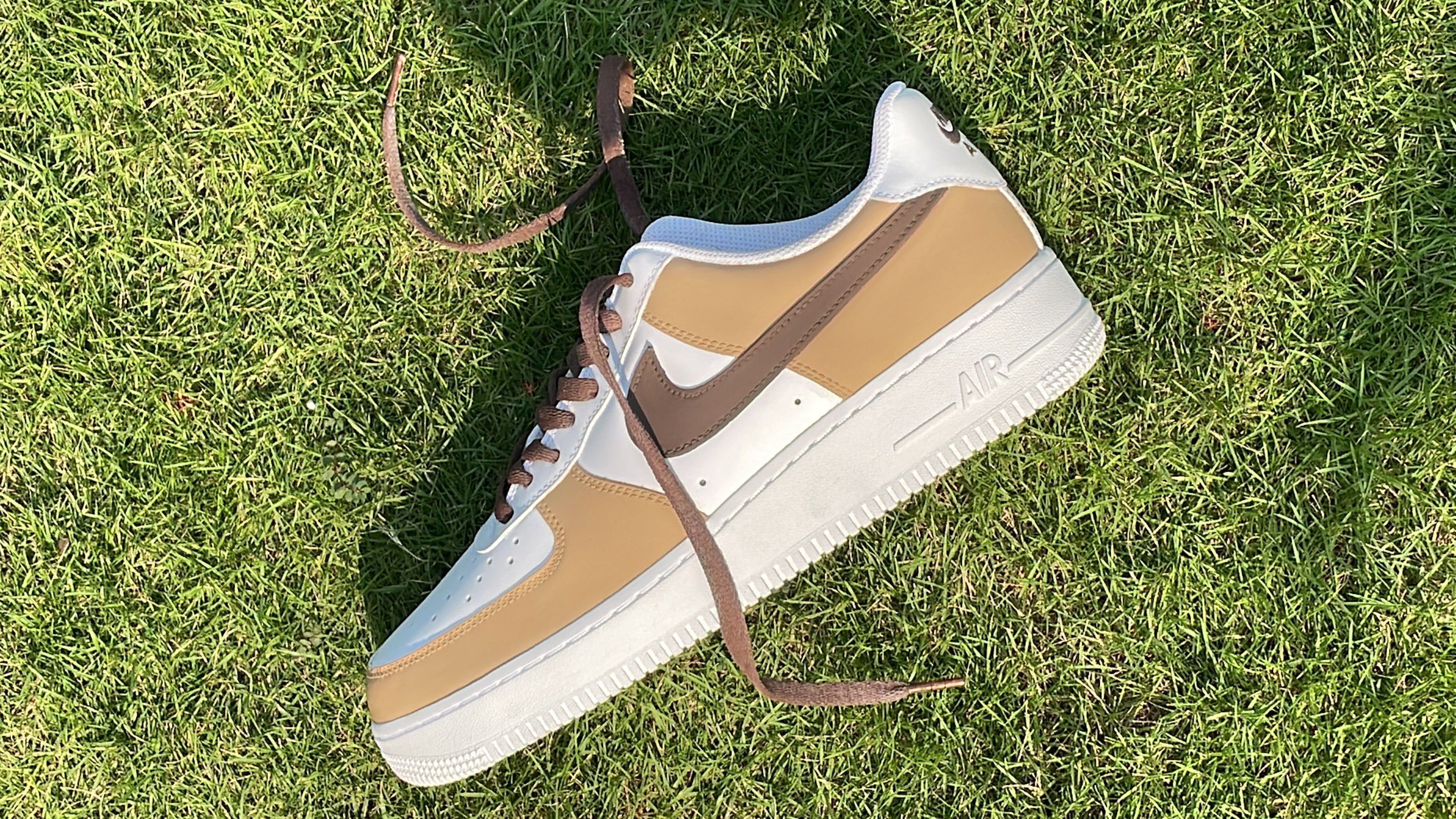 Tan and white streetwear sneaker with brown swoosh on grass, stylish luxury footwear