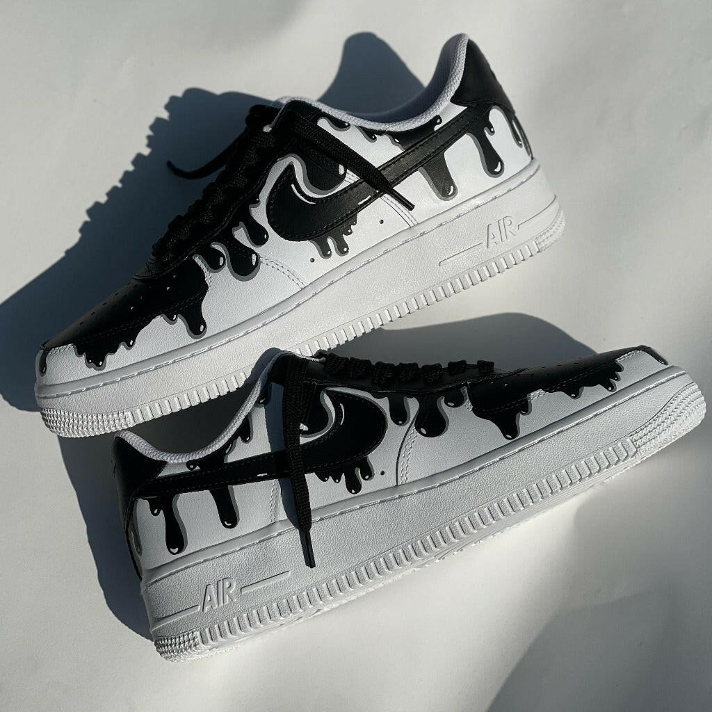 Black and white custom Nike Air Force 1 sneakers with drip paint design on white background.