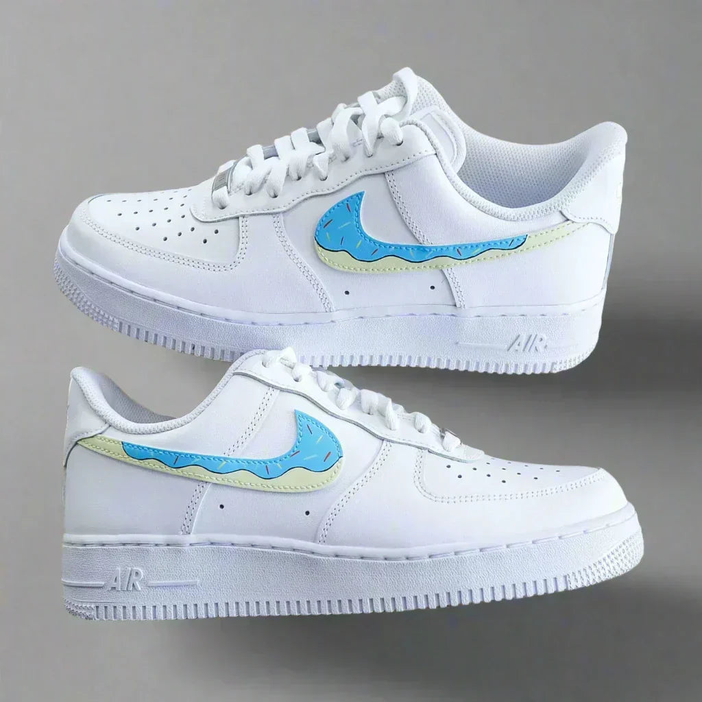 White low-top sneakers with blue and yellow patterned swoosh, streetwear style, on grey background