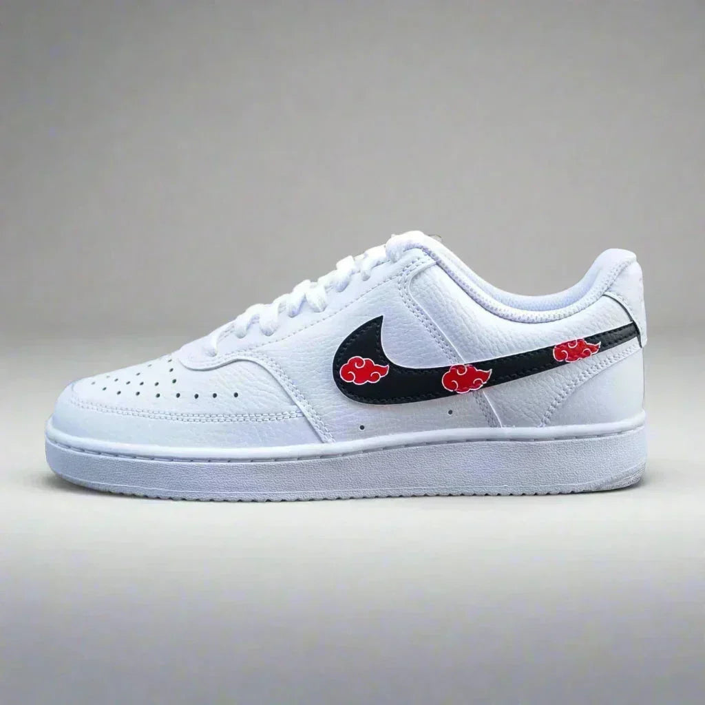 White streetwear sneaker with black swoosh and red cloud accents, designer low-top shoe