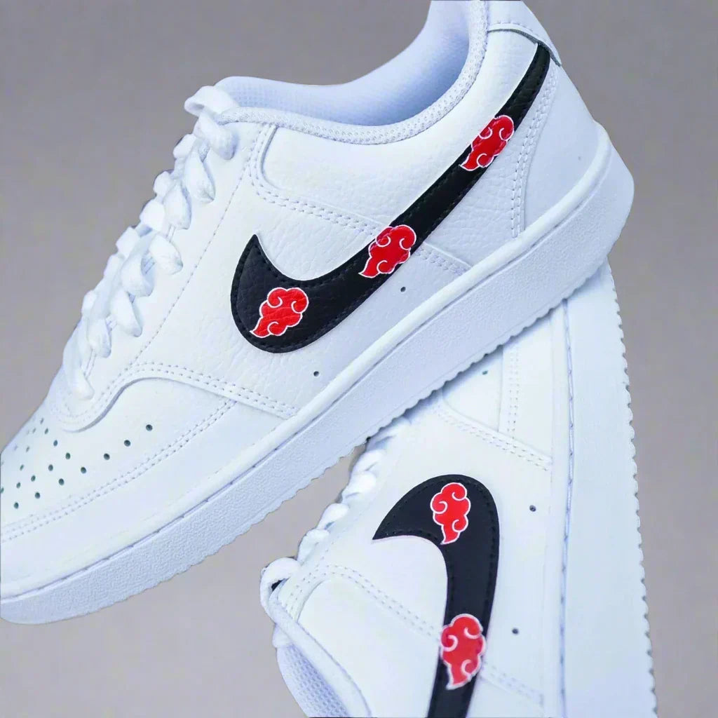 White low-top sneakers with black swoosh and red cloud graphic, streetwear style footwear