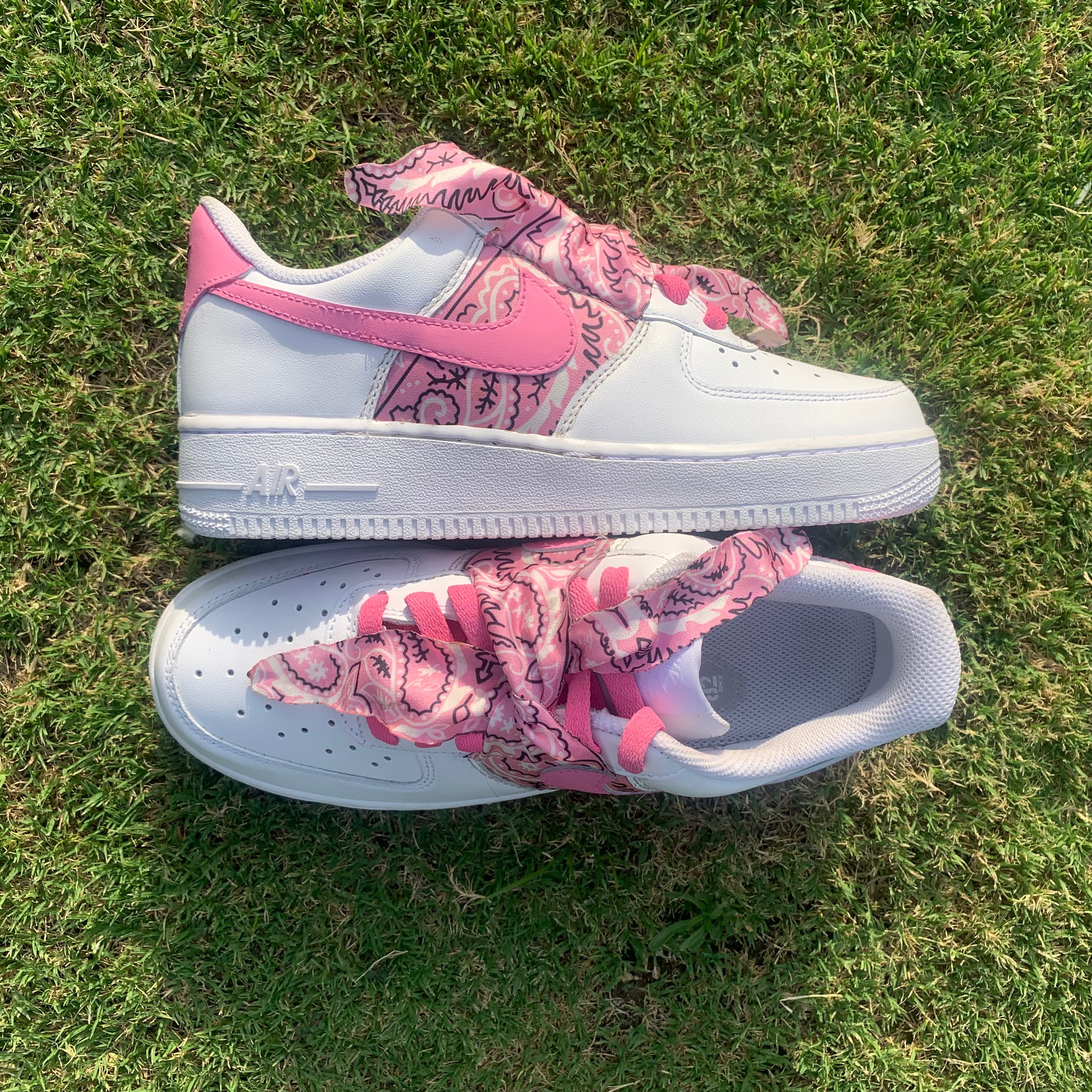 White and pink sneakers with paisley bandana laces and details, on green grass