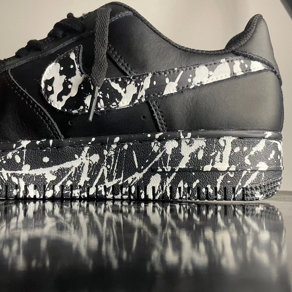 Black streetwear sneaker with white paint splatter design on side and sole