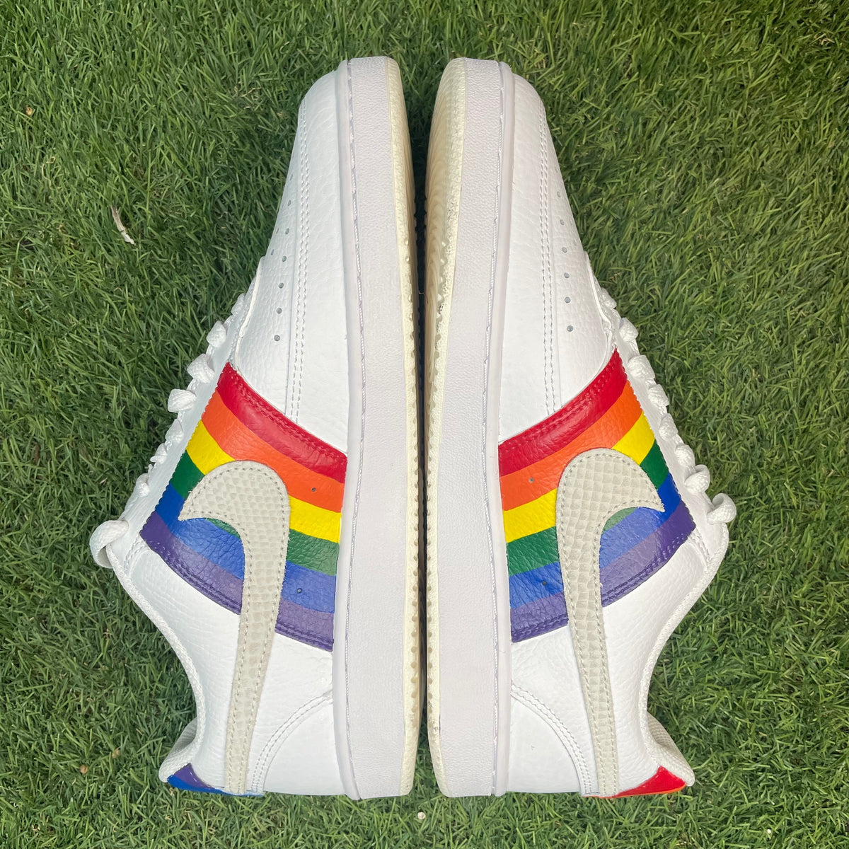 White leather sneakers with rainbow stripes and textured swoosh on grass, streetwear shoes
