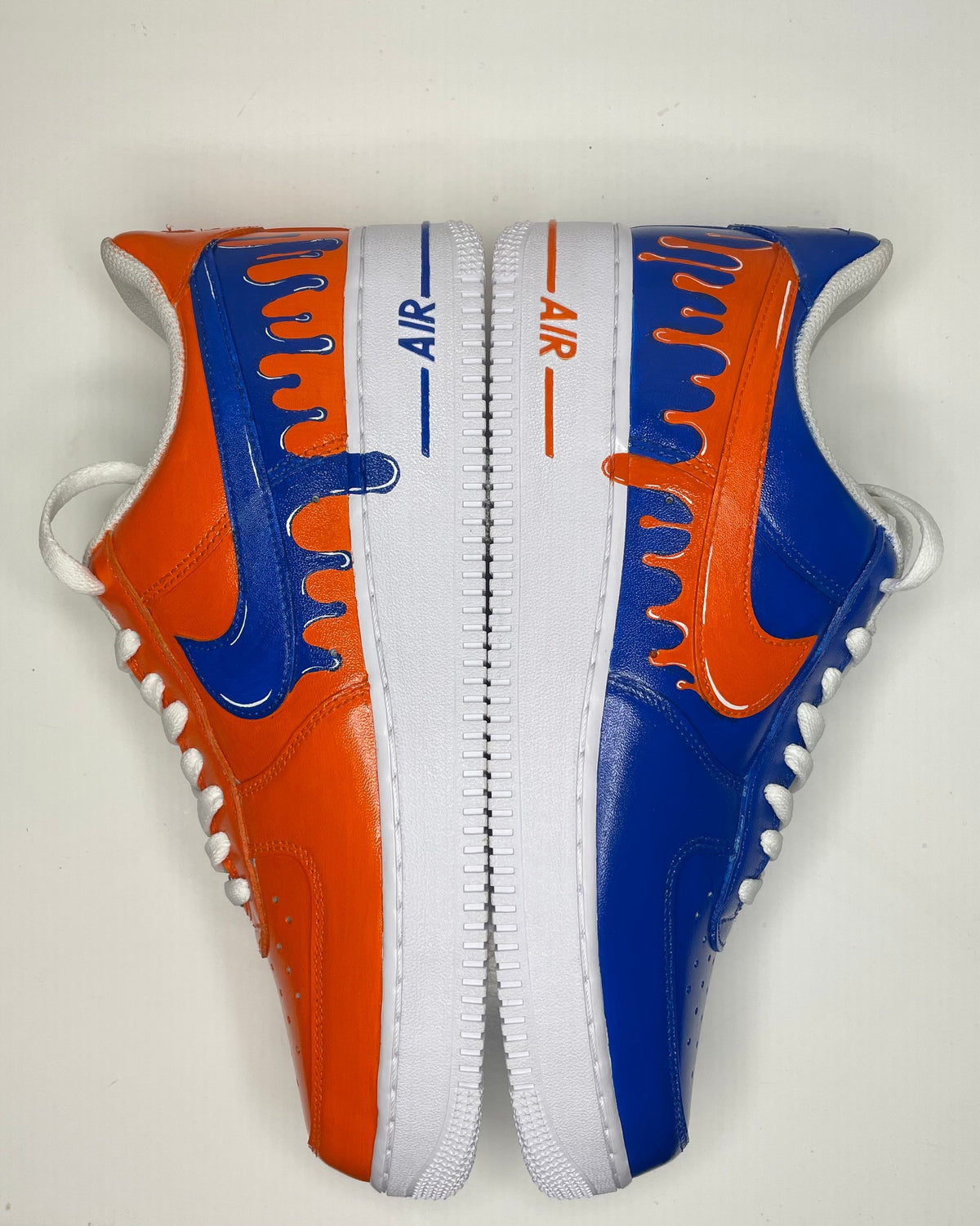 Custom streetwear sneakers with blue and orange drip paint design, white sole, and AIR logo